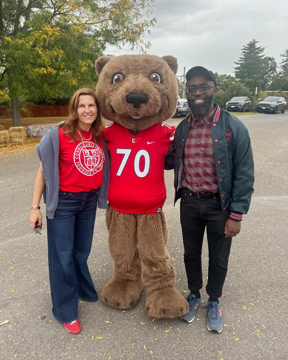 two people posing with Cornell bear mascot Touchdown