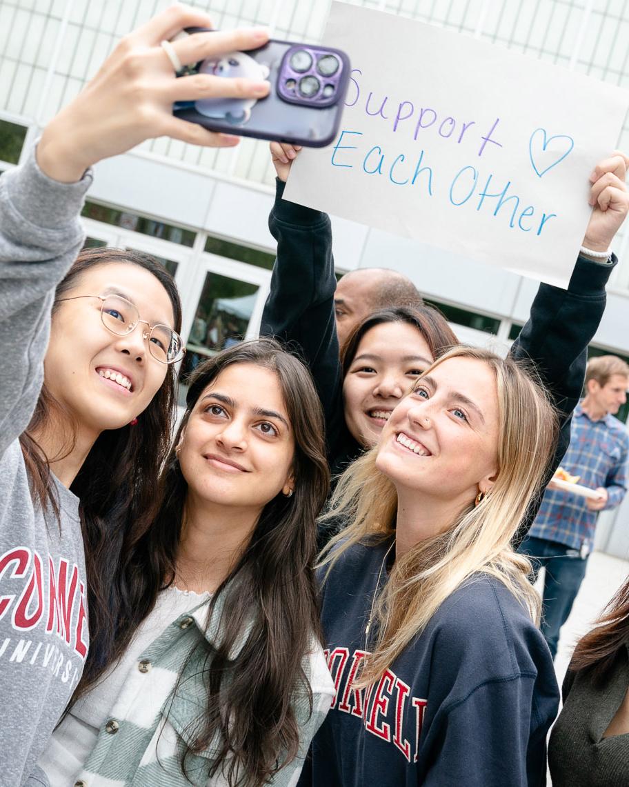 group of students take a selfie and holding up a sign