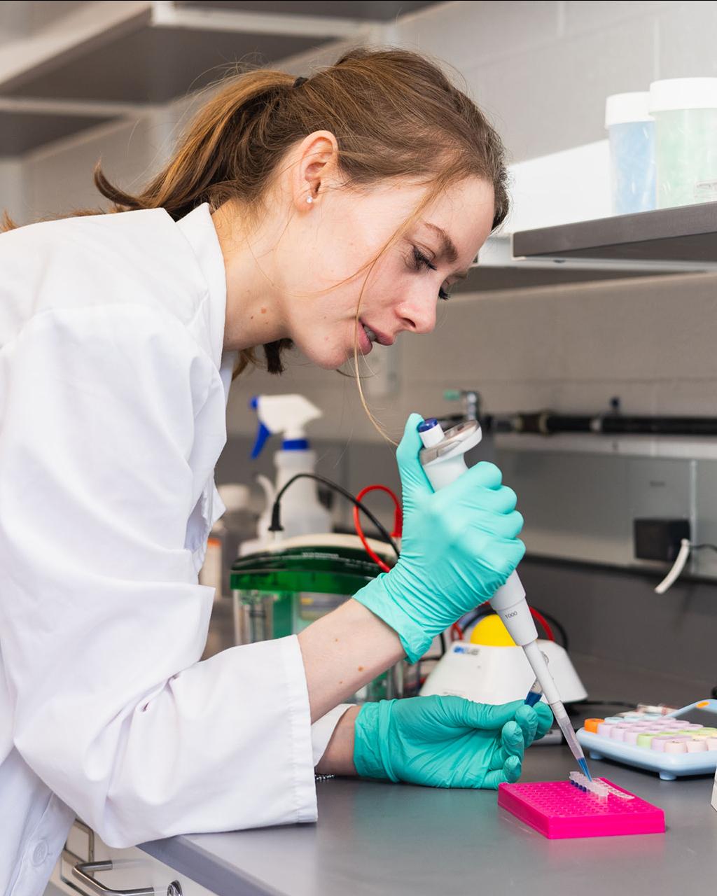graduate student in a while coat pipettes samples