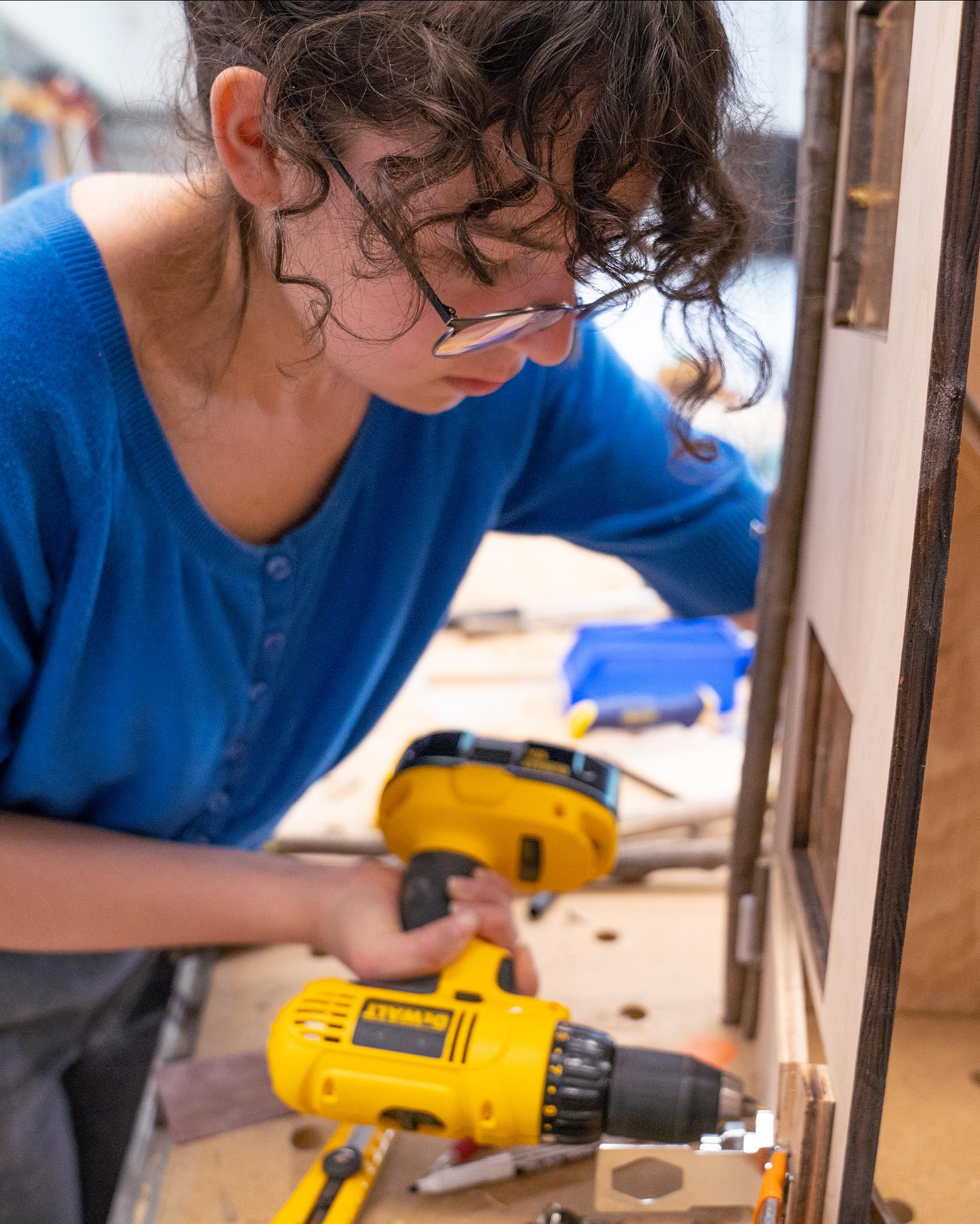college student using a drill in a workshop