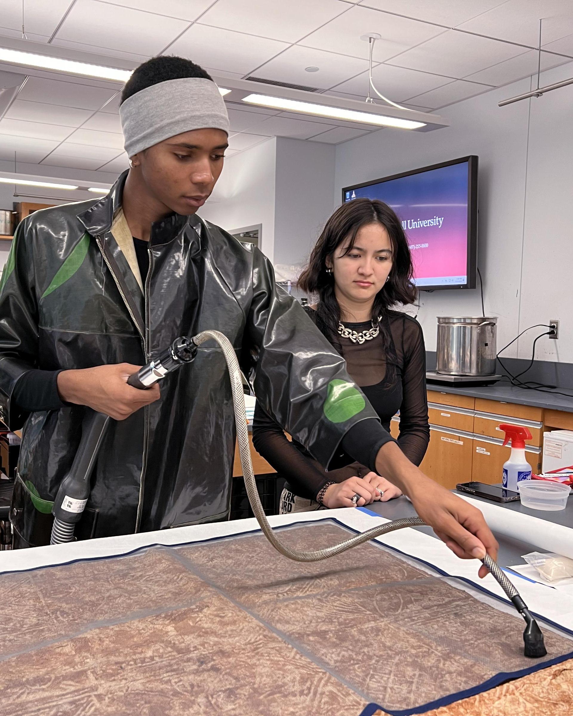 student using a device on a piece of fabric stretched out on a table