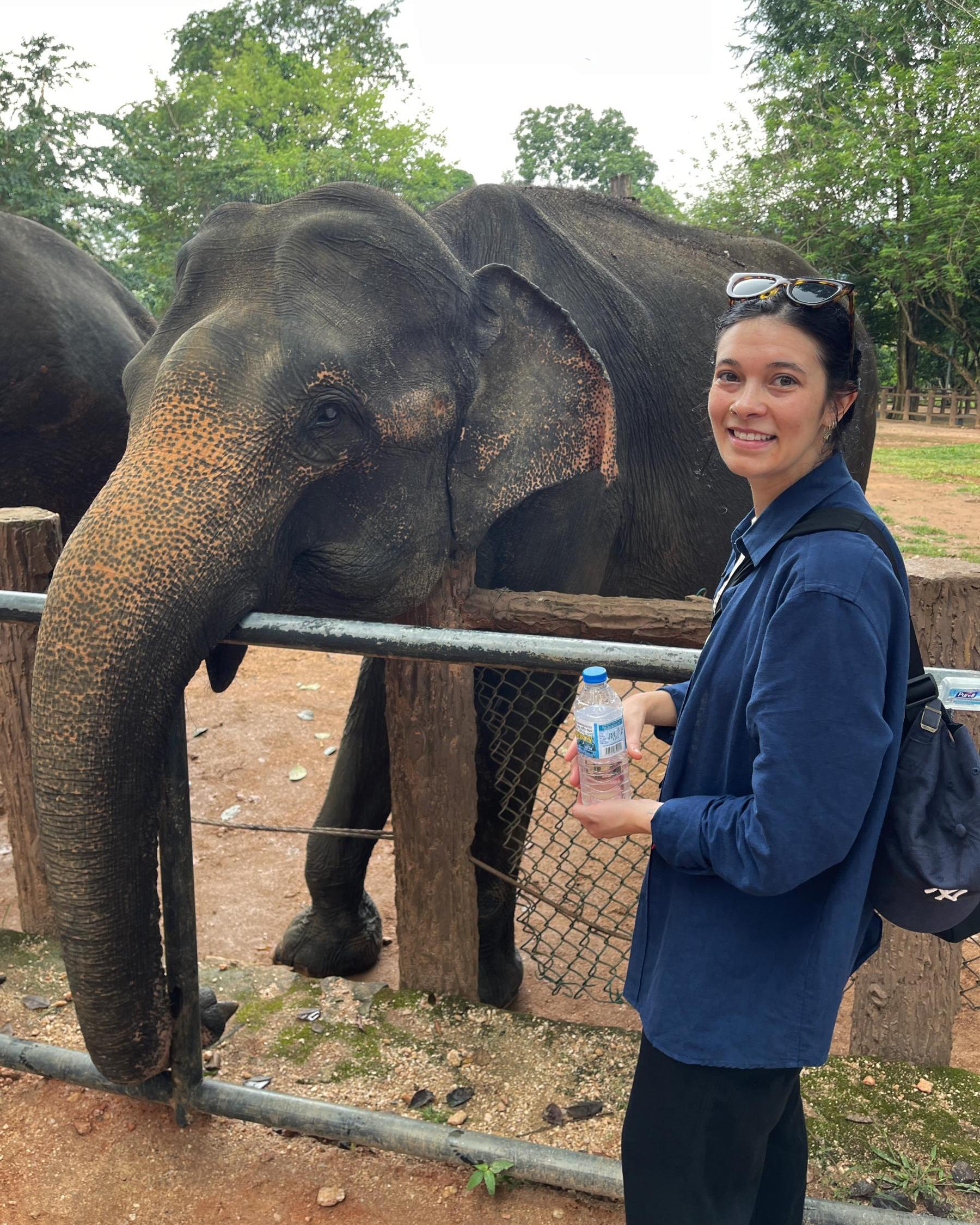 Sephra stands next to an elephant at a sanctuary