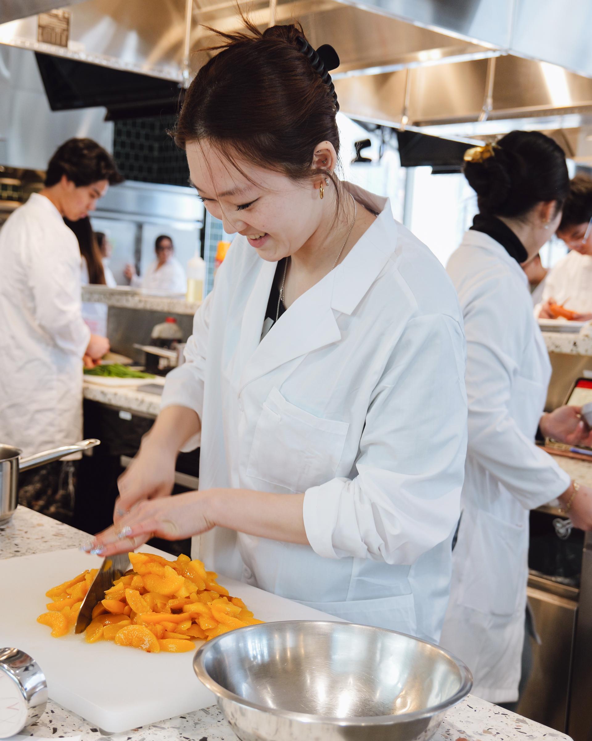 A student cutting peaches in the Discovery Kitchen