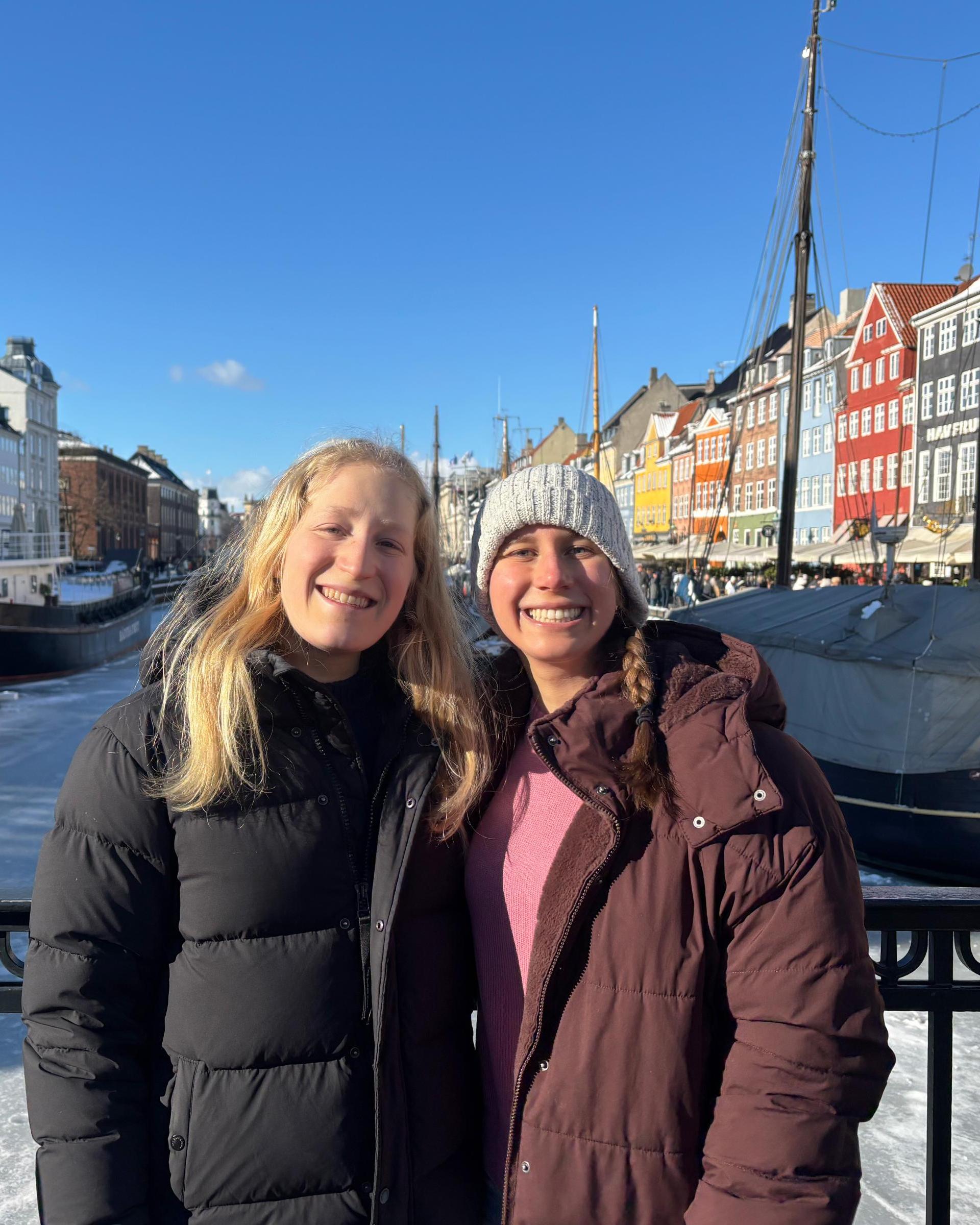 Two women pose on a bridge by a frozen canal in Amsterdam
