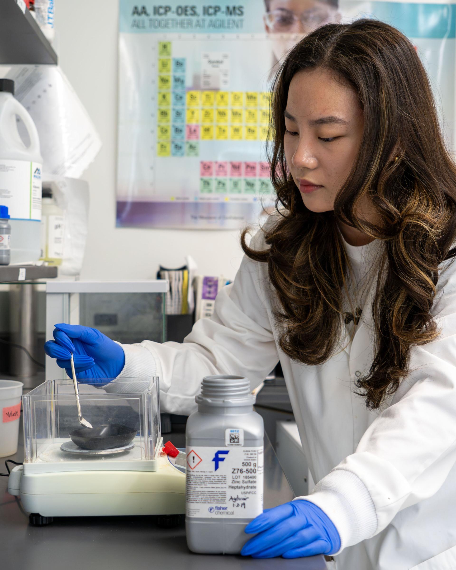 A student pouring a mixture into a bowl in a lab