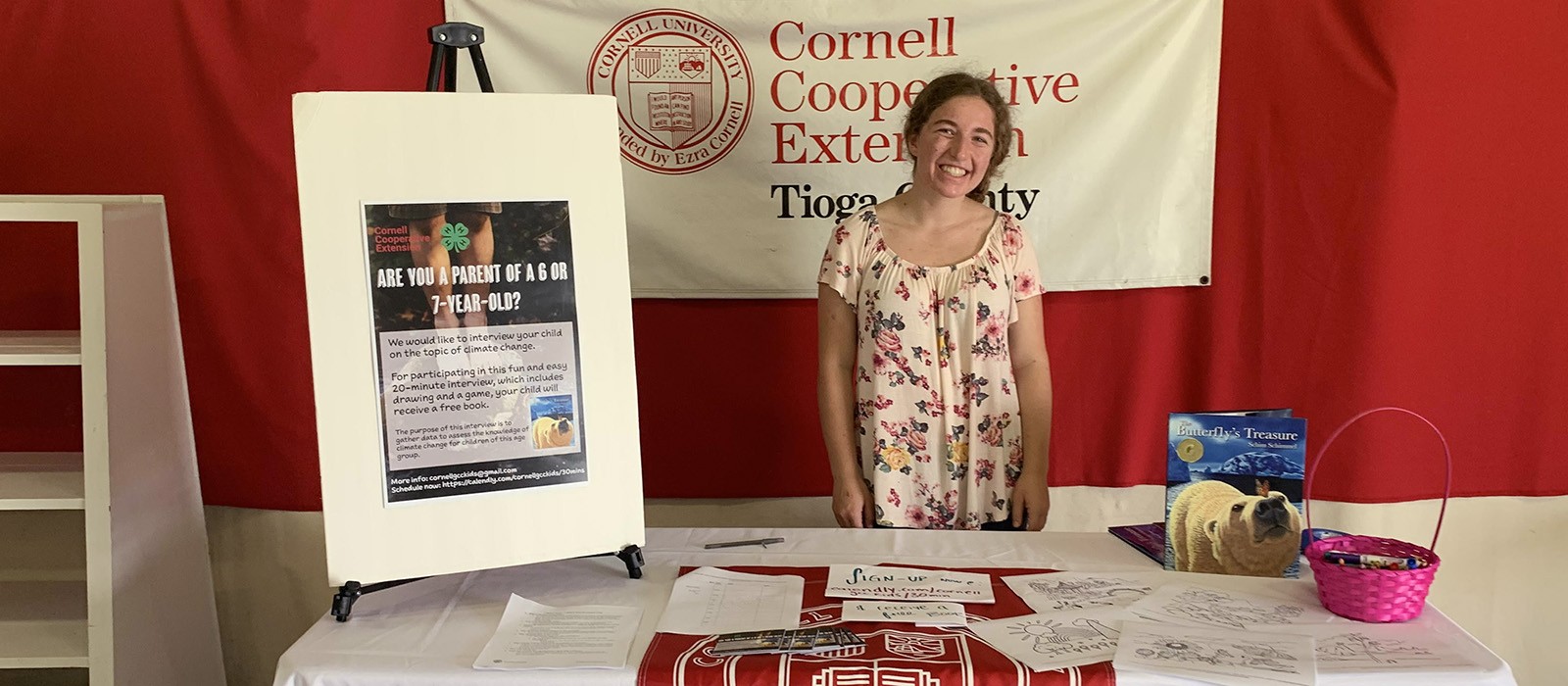 woman at a table with Cornell Cooperative Extension sign behind her