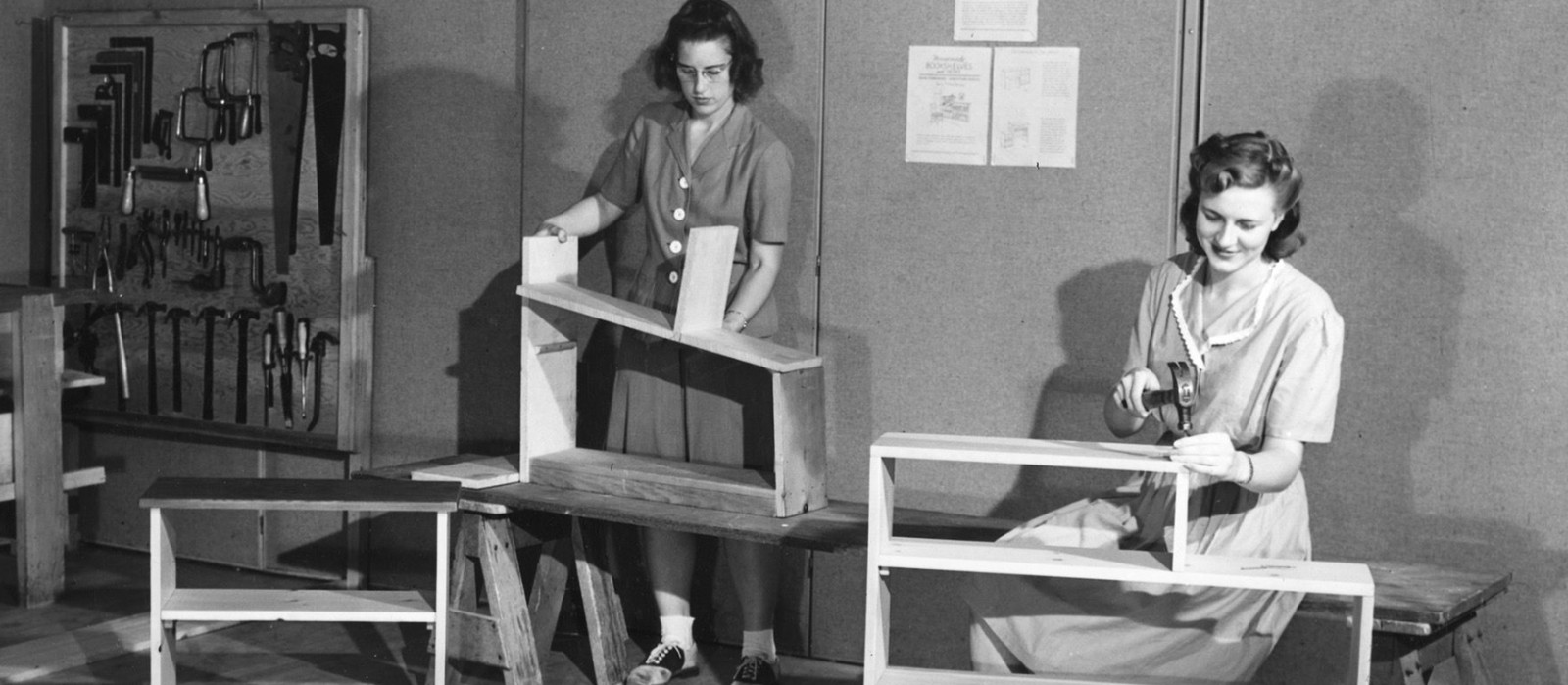 two women in dresses constructing wooden furniture in the 1940s or 50s