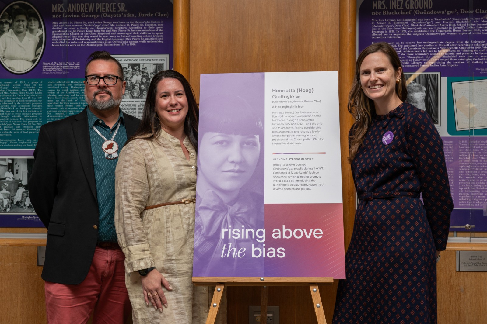 Three people stand with poster