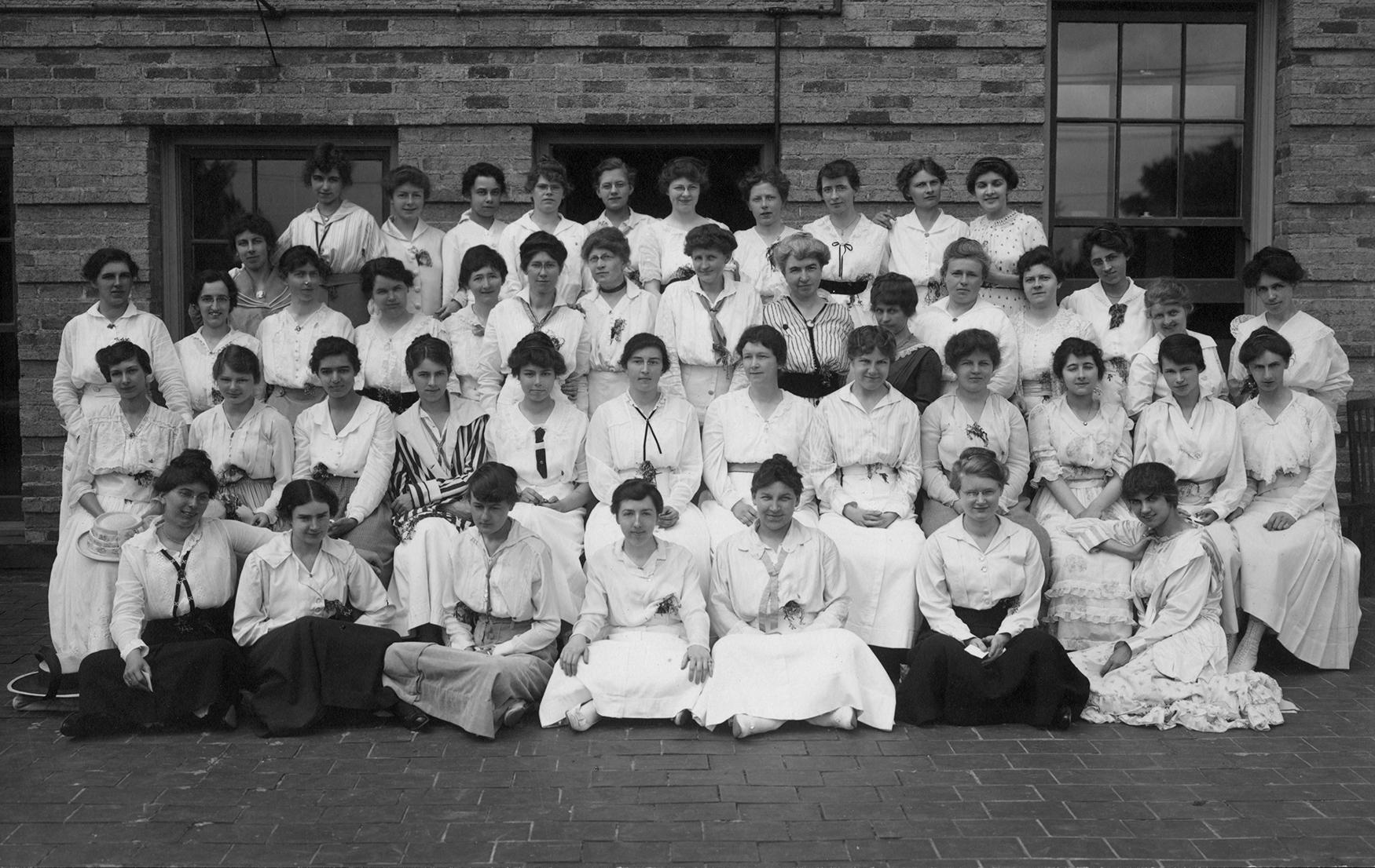 group of about 60 women in white outfits sitting in rows