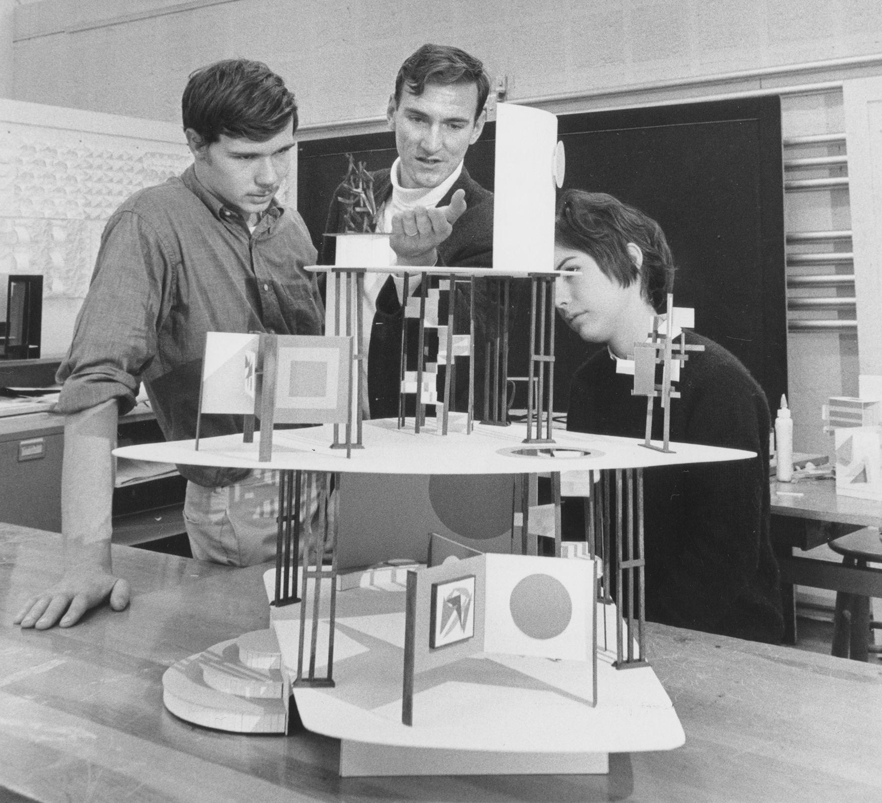 Three students examine a 3-D wooden model in a studio