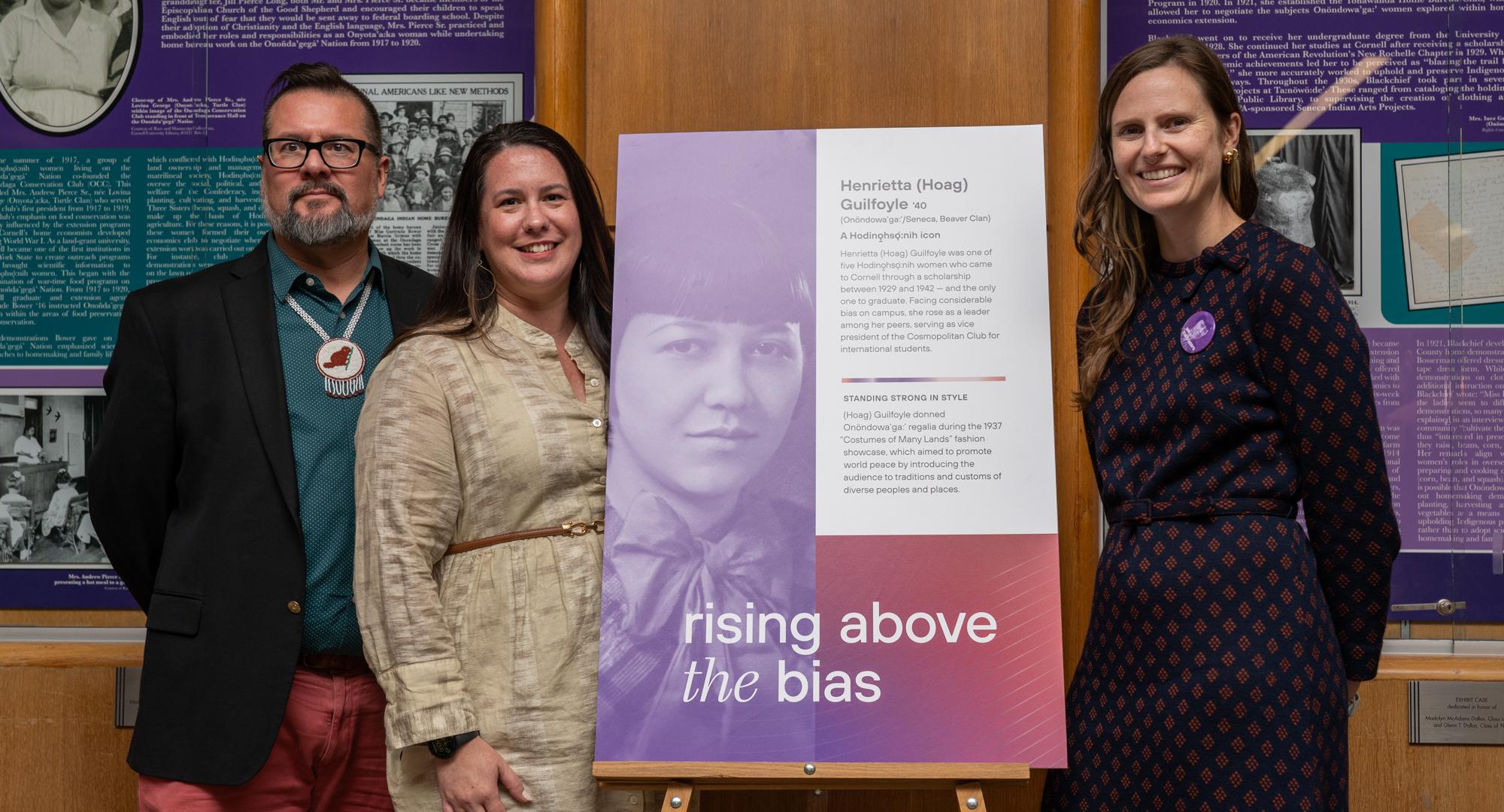 Three people stand with poster