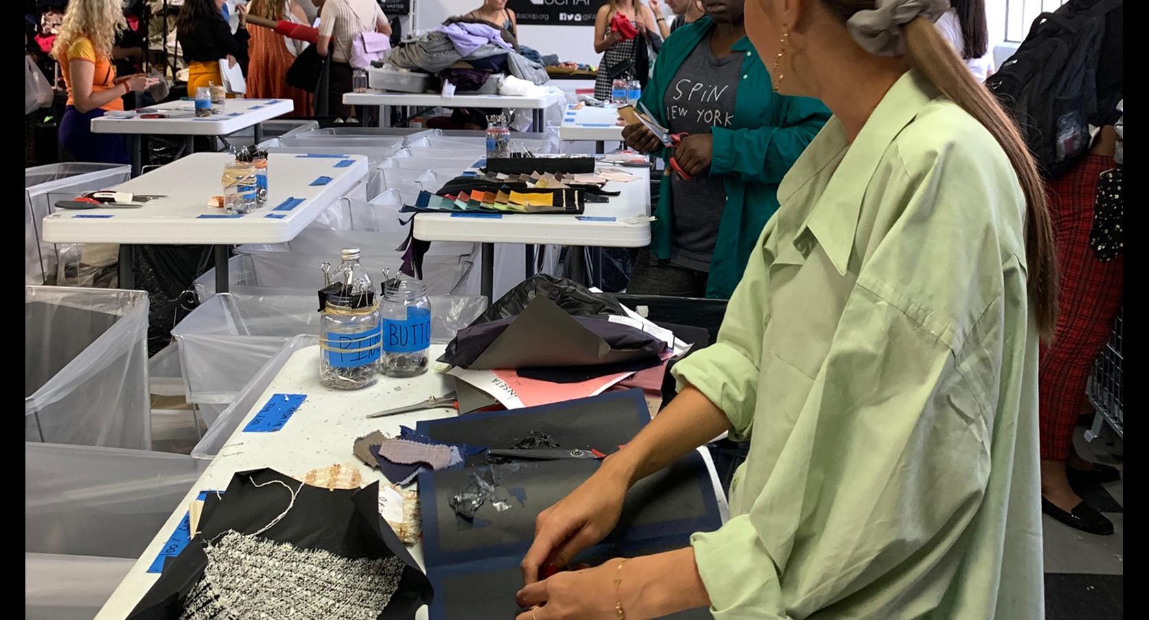 People working with piles of fabric on tables 