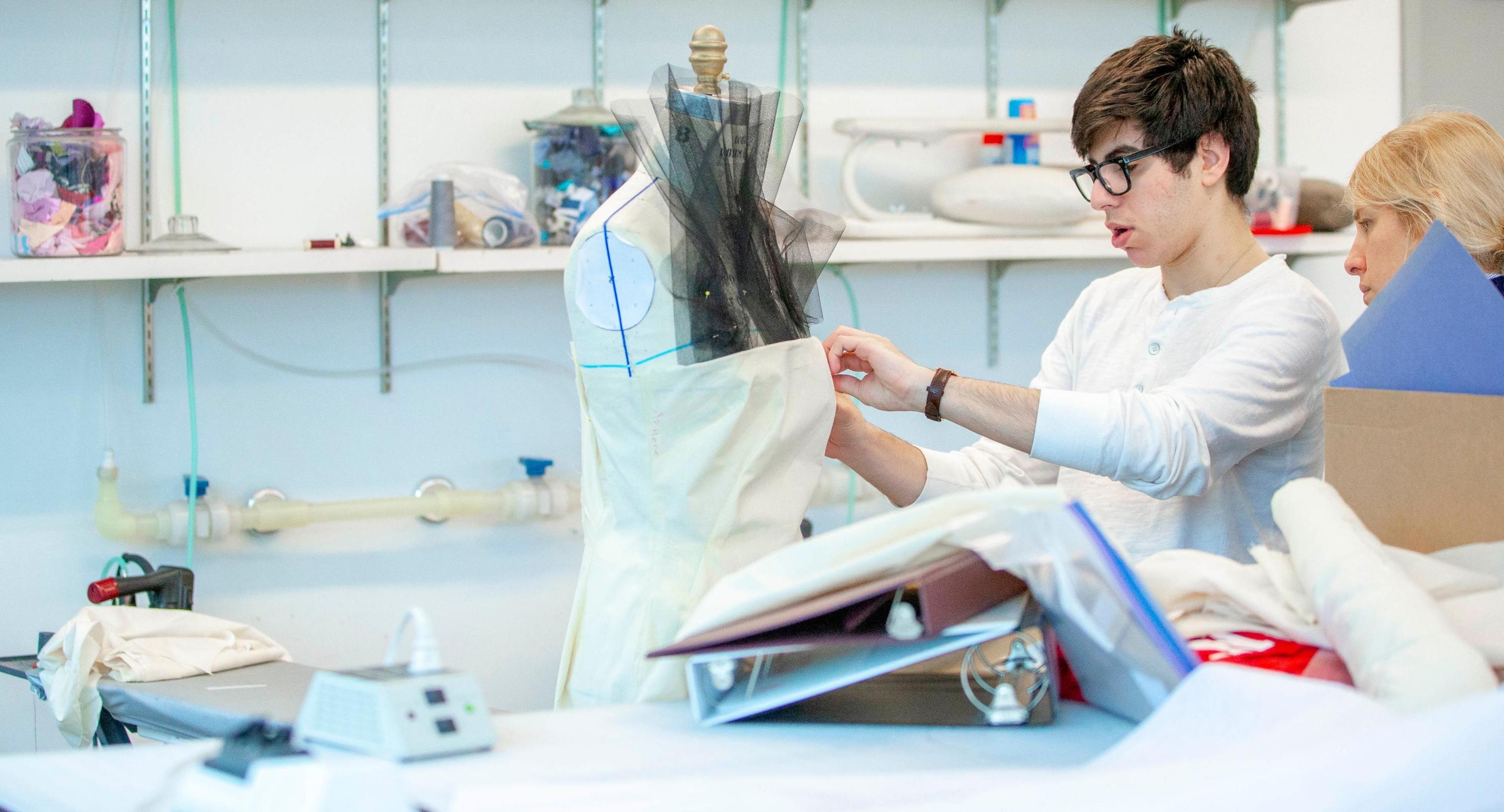 college student working on a dress on a mannequin