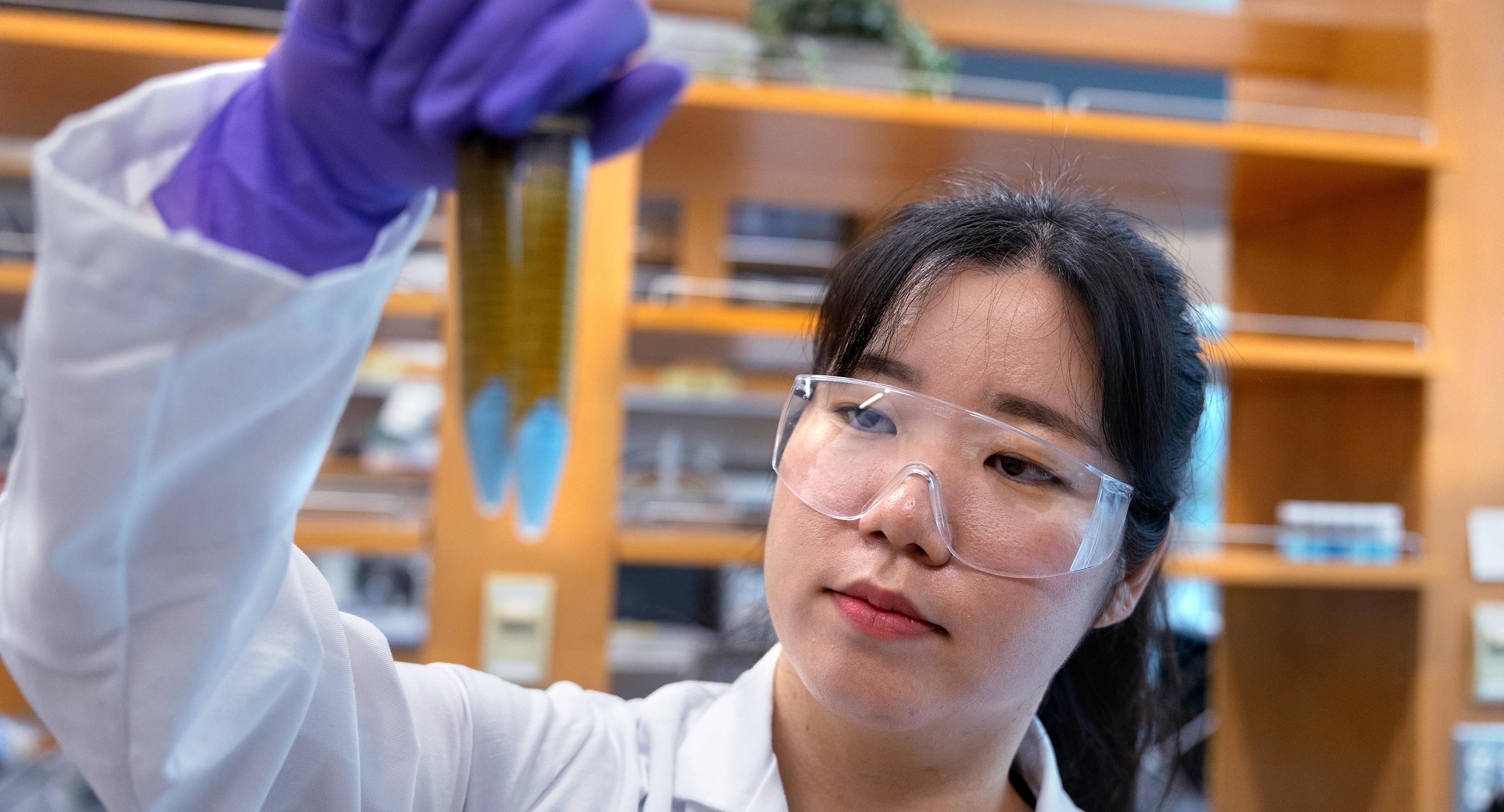 scientist in a lab coat holding up test tubes