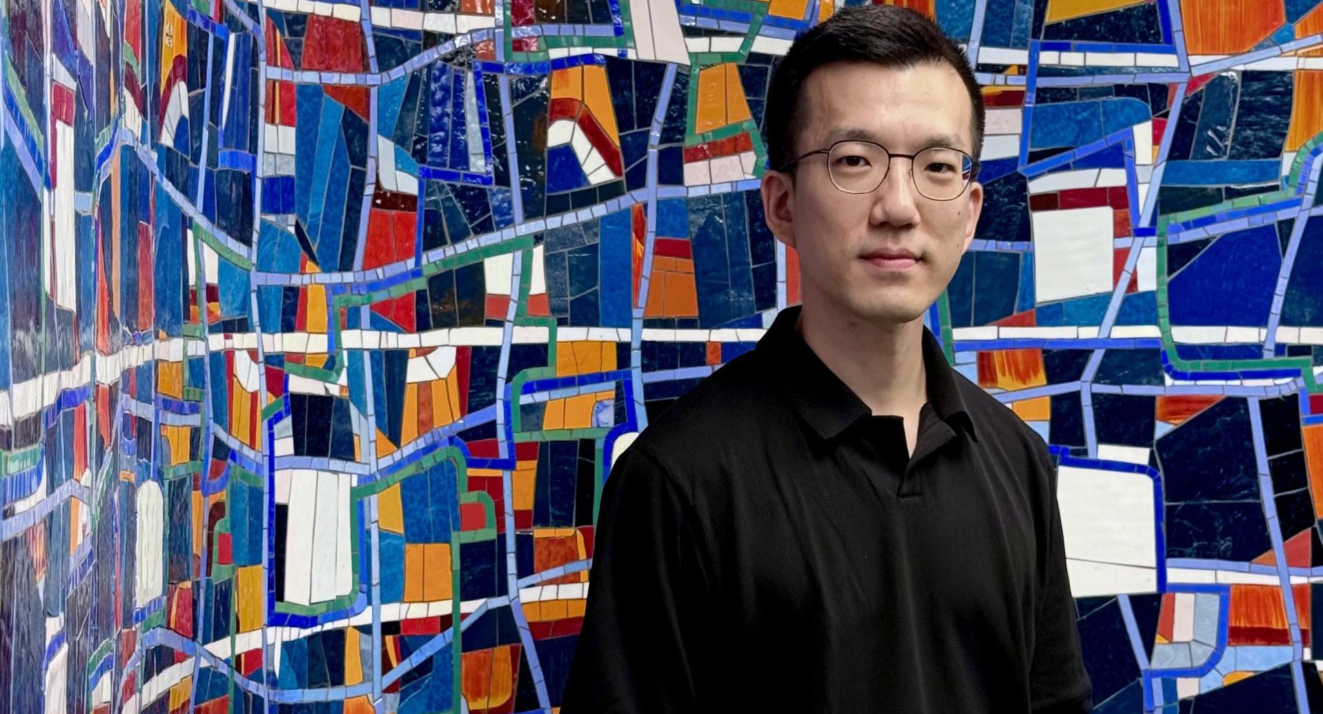 Eddy Man Kim stands in front of the mosaic 