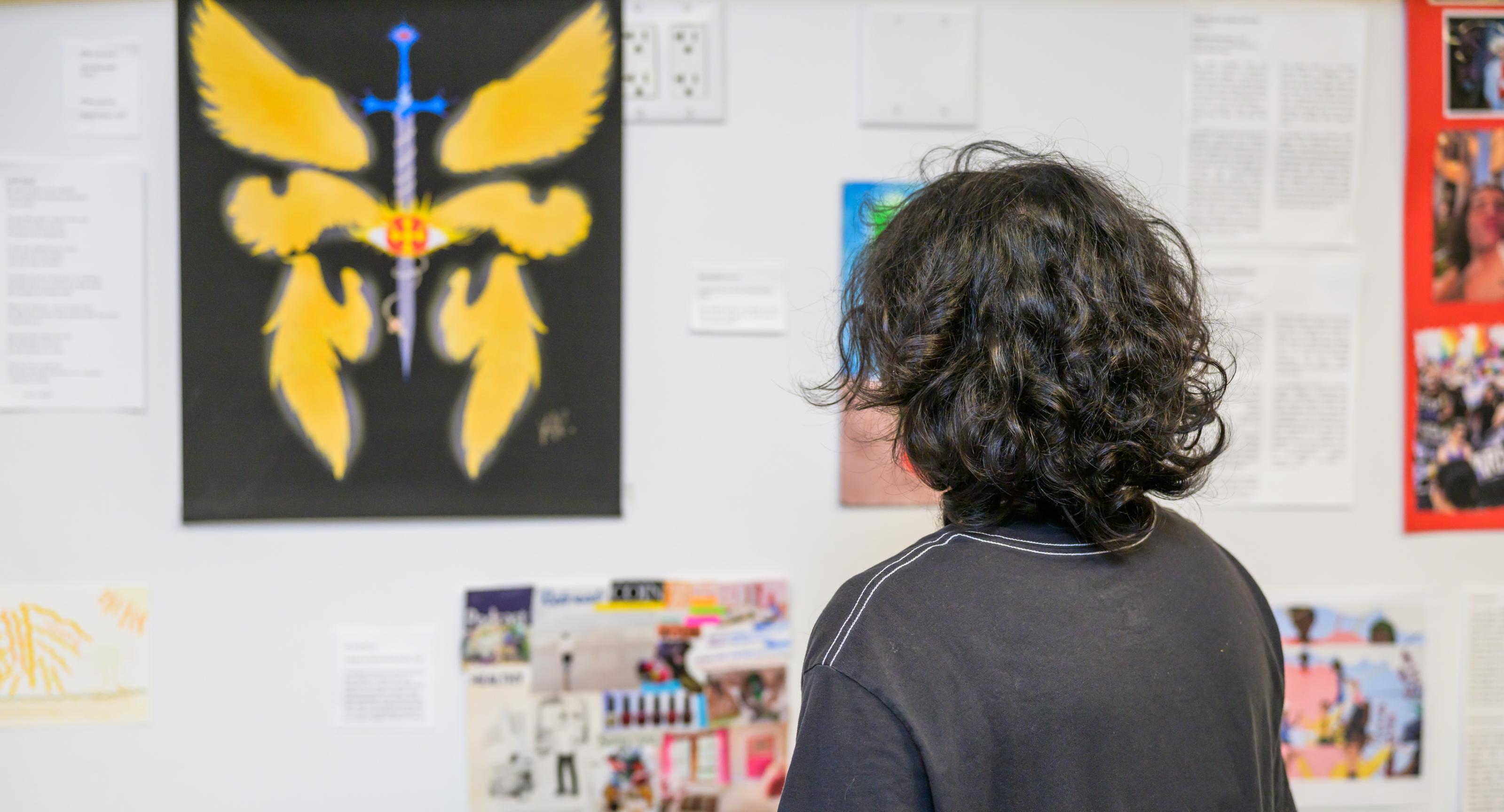 One of the artists from The Ali Forney Center in New York City looks at artwork on display.