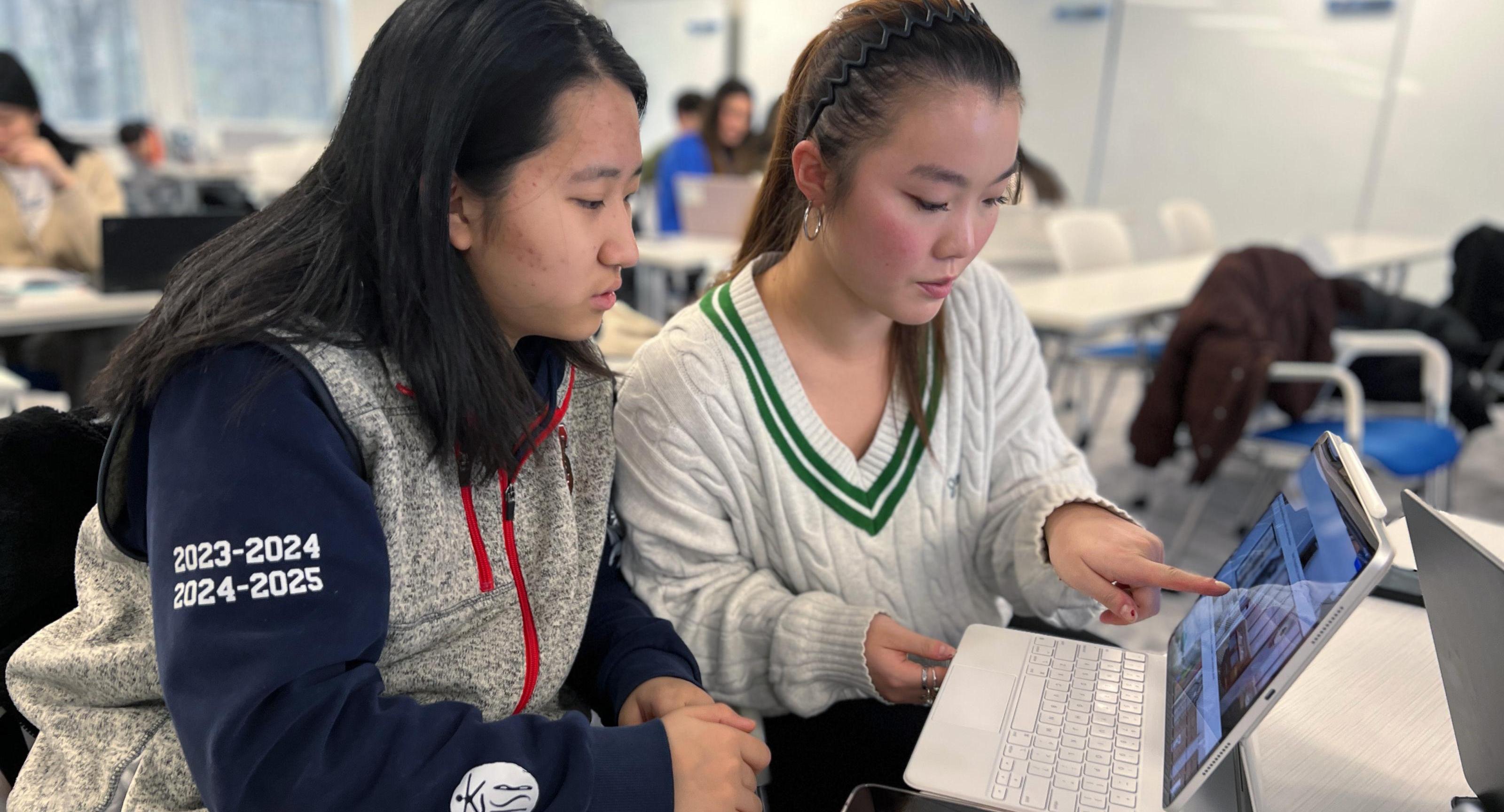 Two students work together on their hotel room design plan 