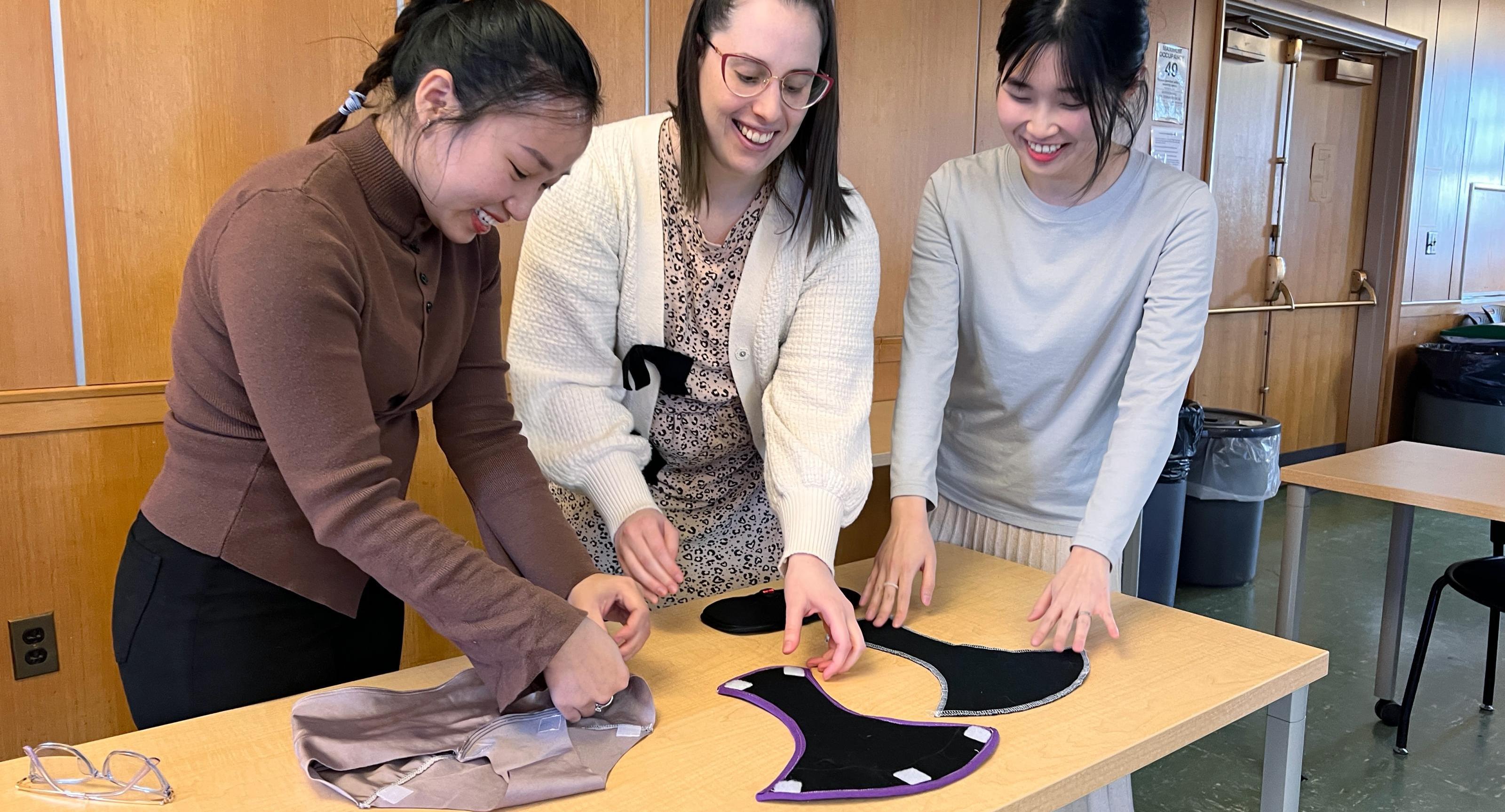 3 women work on inserting fabrics together on their prototype