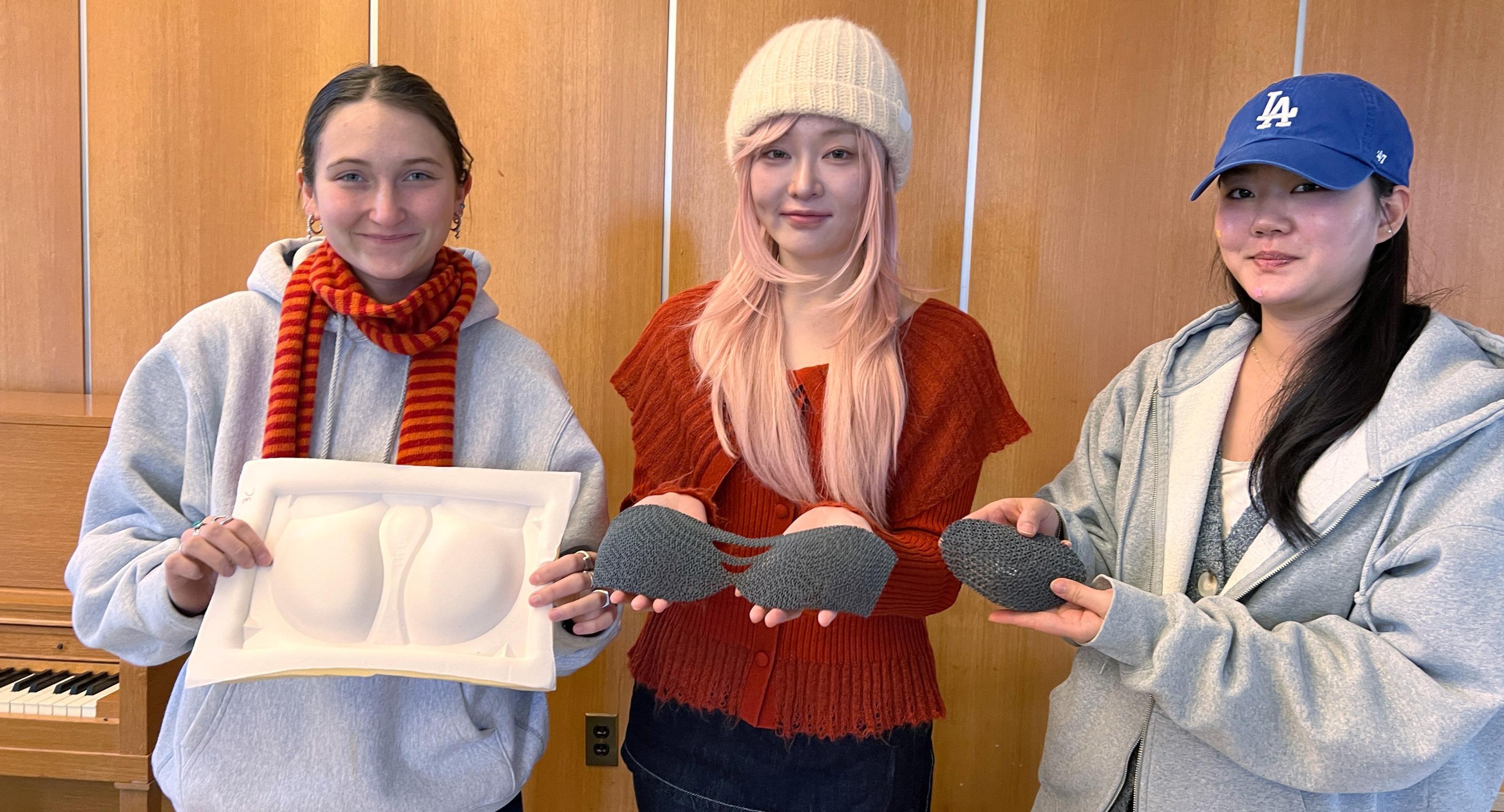 Three students hold up their student designs for a sports bra insert