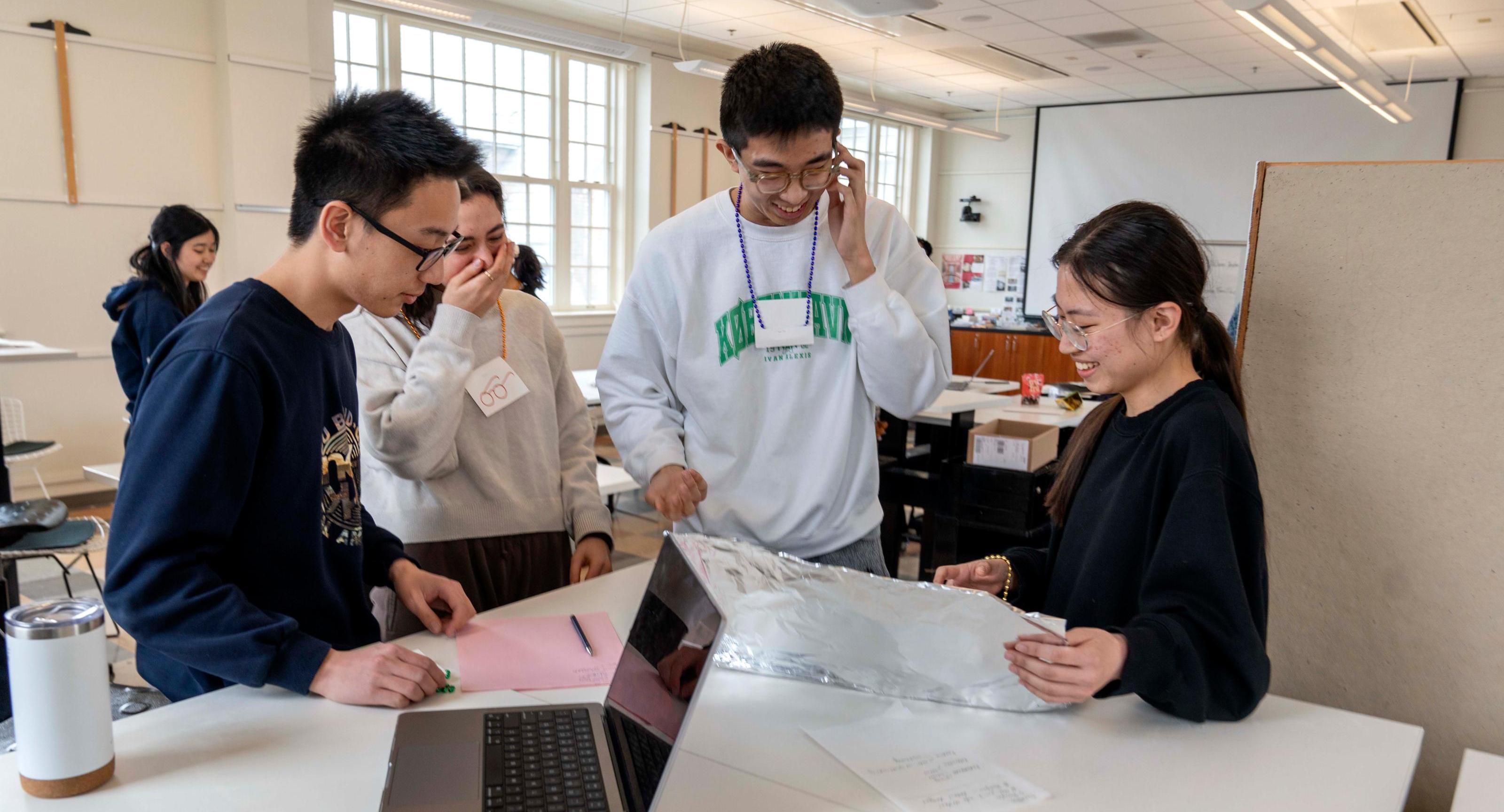 4 students laugh as they work on a design project