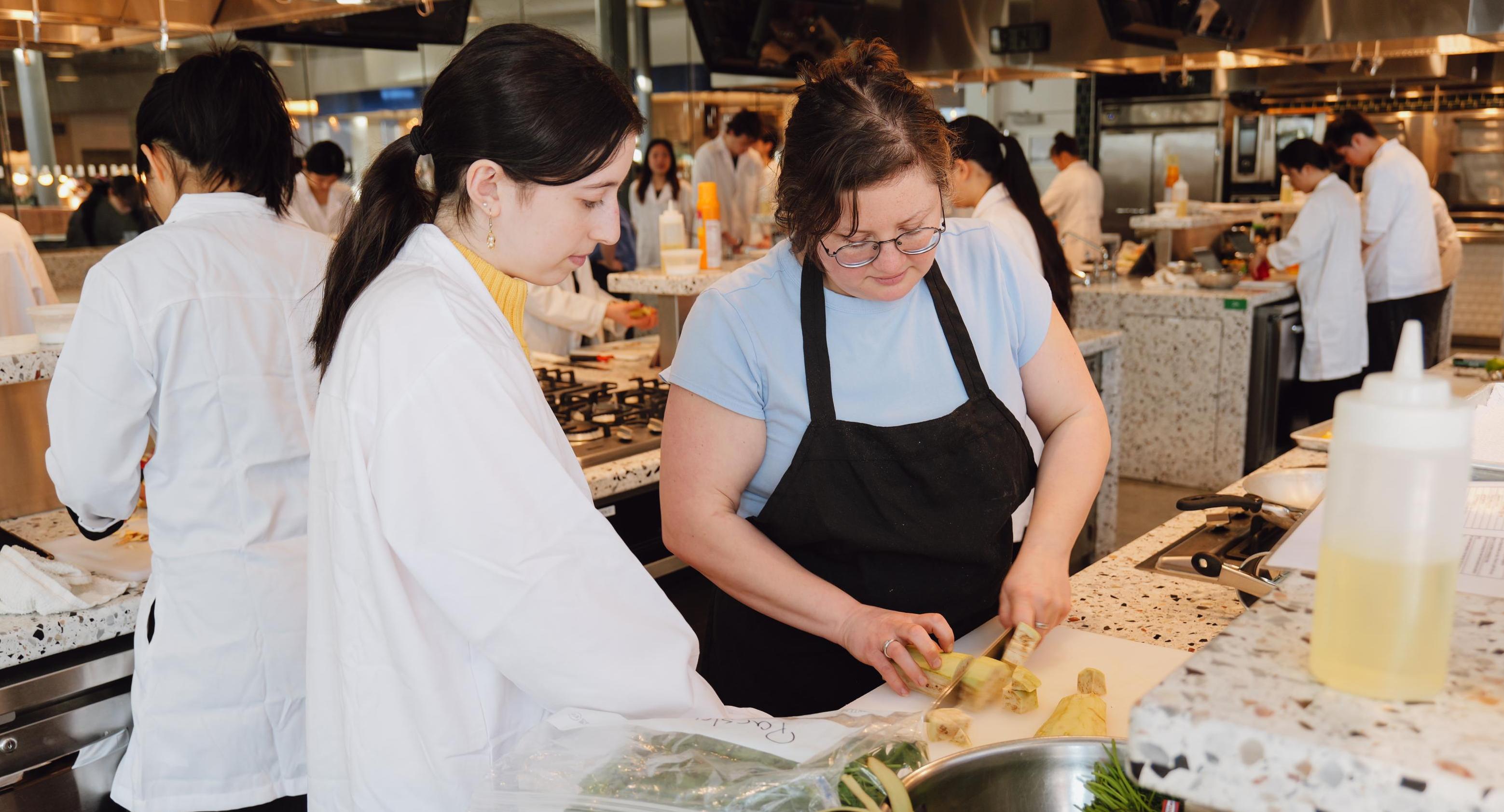 Mandy Bates cutting vegetables with a student in the Discovery Kitchen