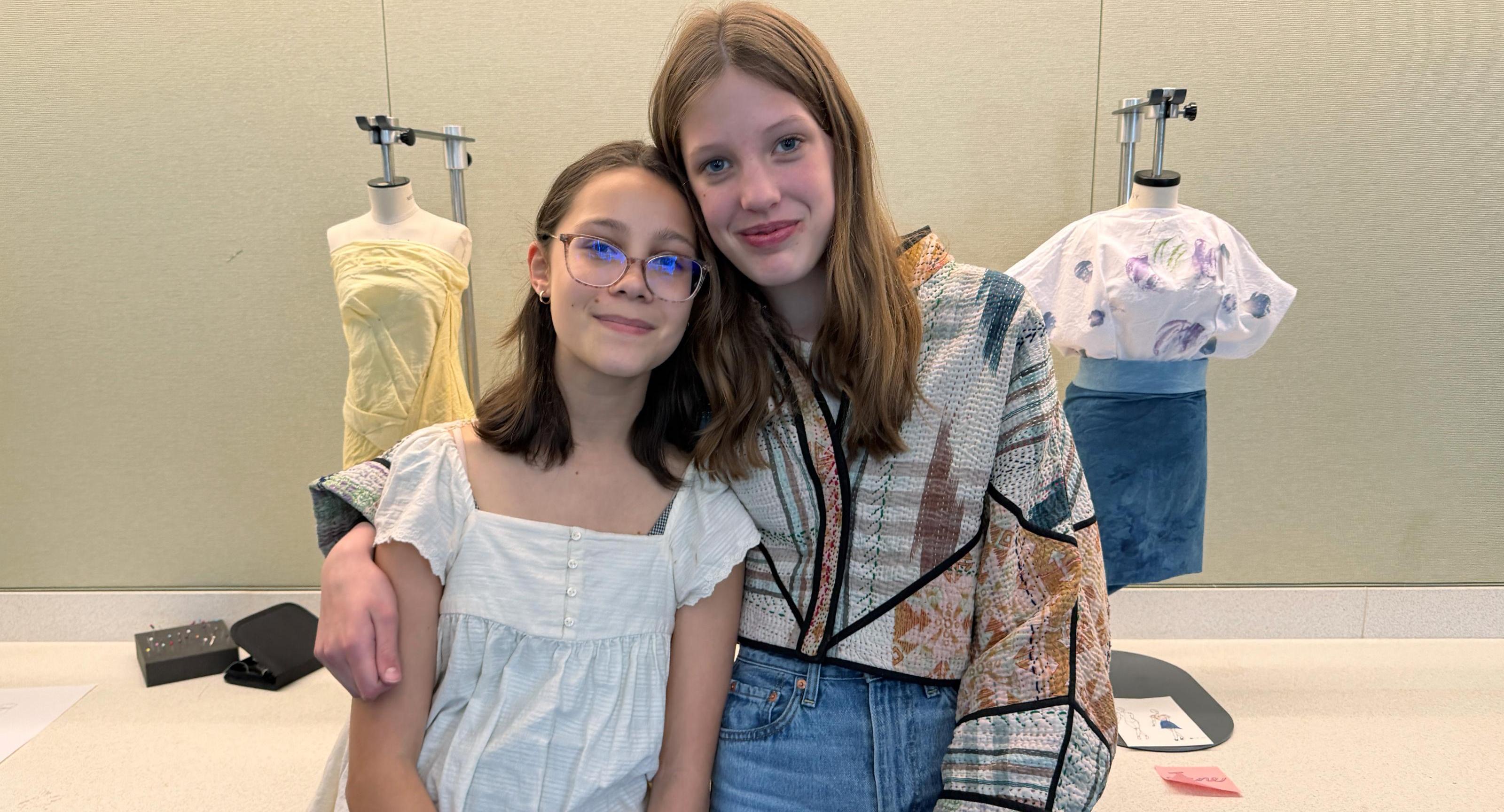 Two students pose with their dress form fashions