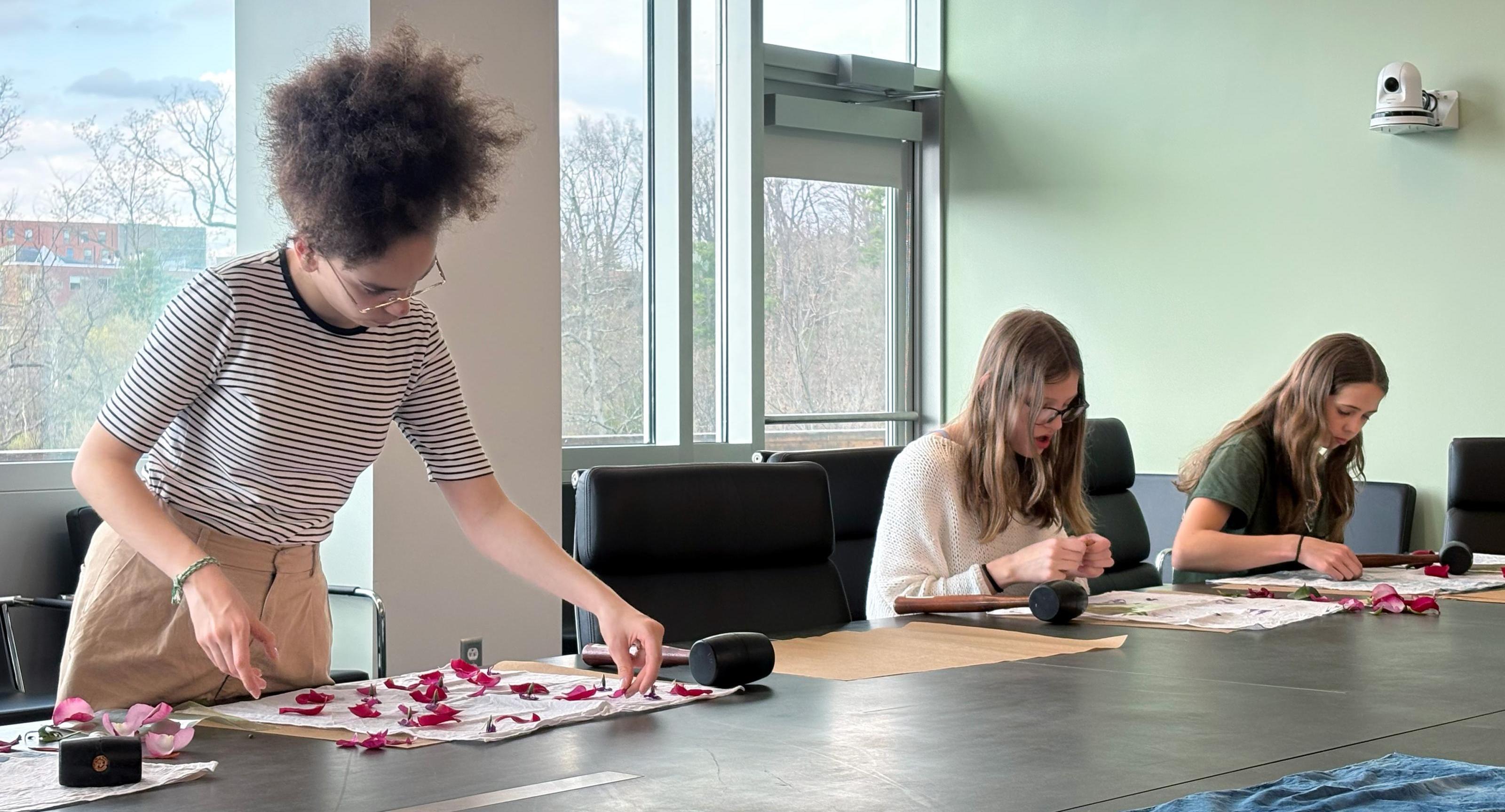 students pound flower petals with a rubber mallet