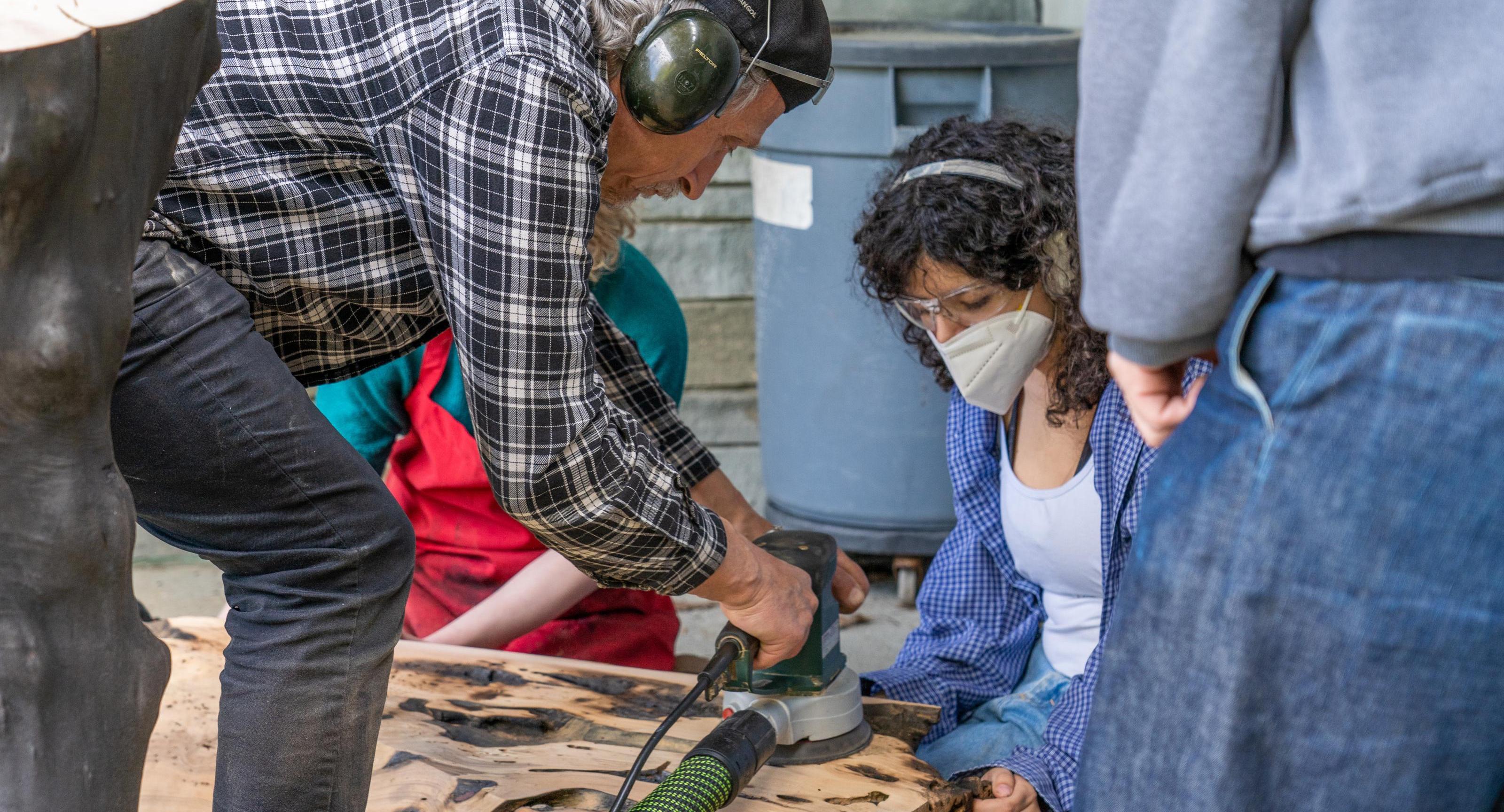 Jack Elliott teaches students to sand a bench