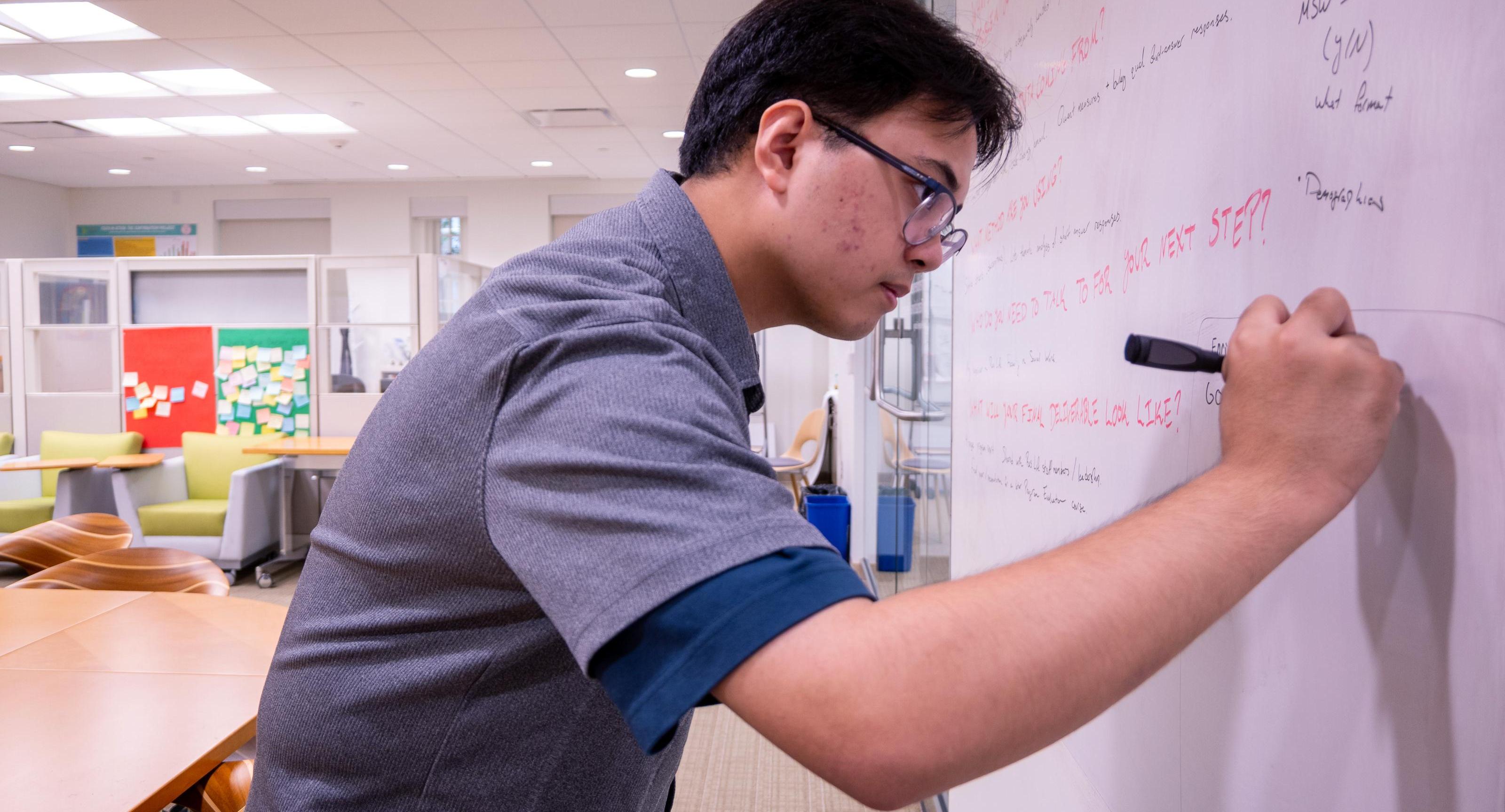 A student writes on a marker board