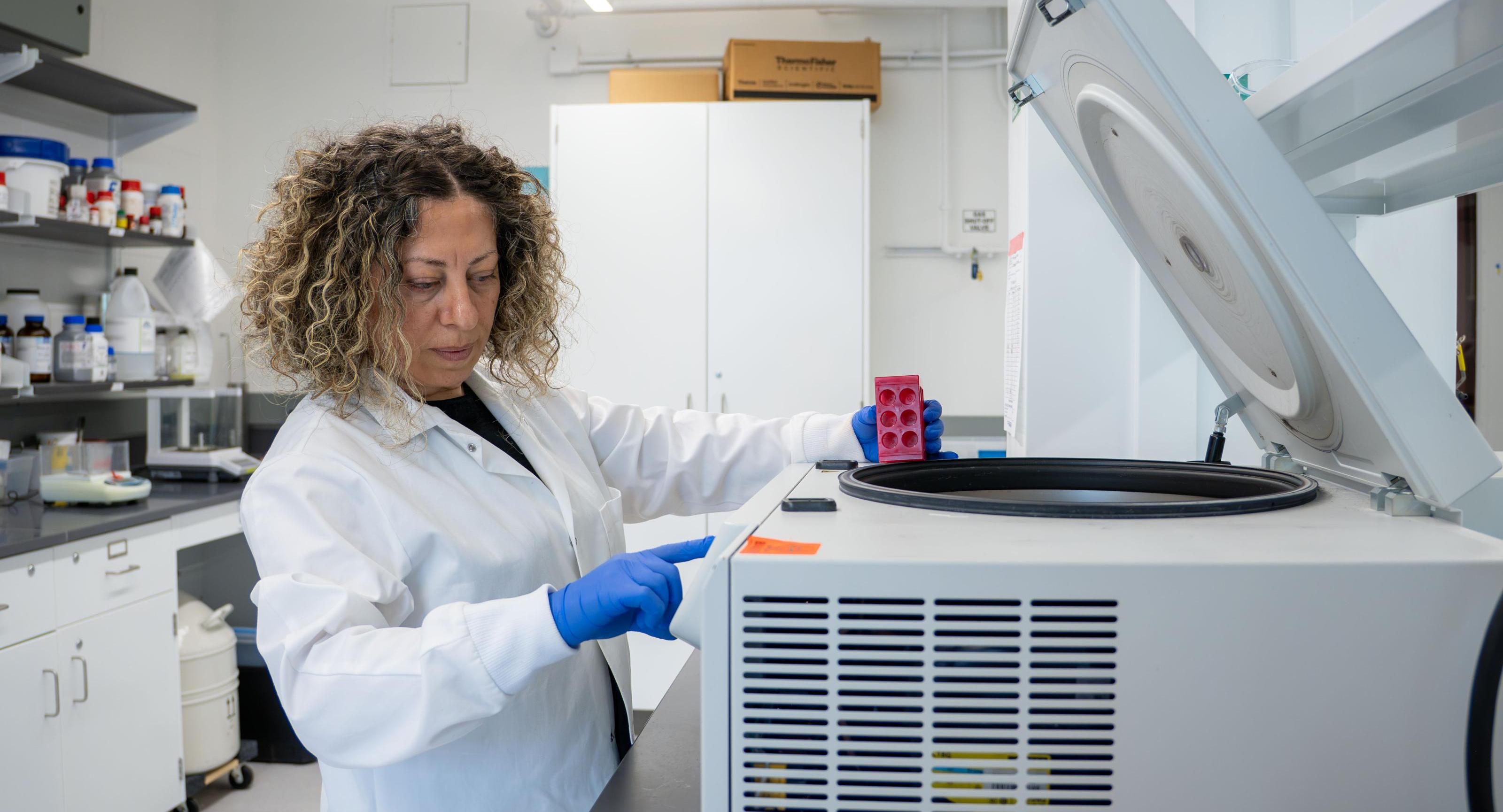 A faculty member working with a centrifuge in a lab.