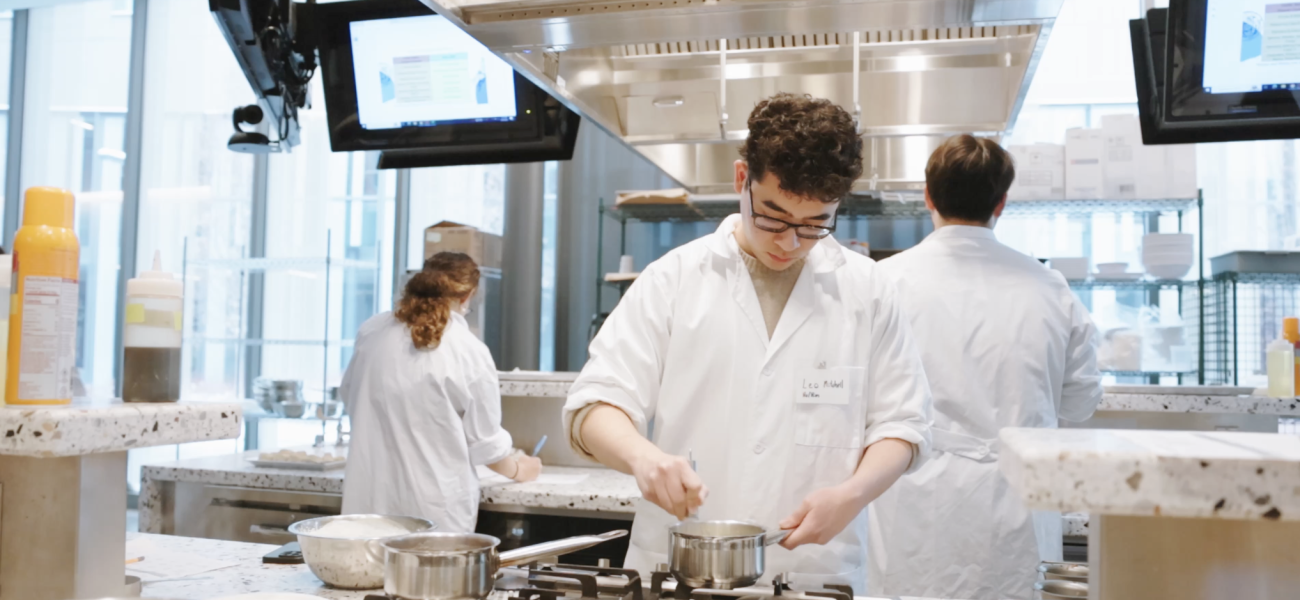 A student whisking ingredients inside a pot in the Discovery Kitchen