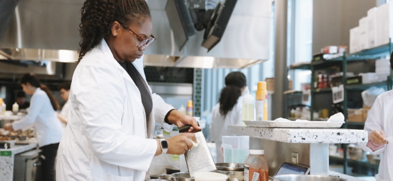 A student grating cheese in the Discovery Kitchen. 