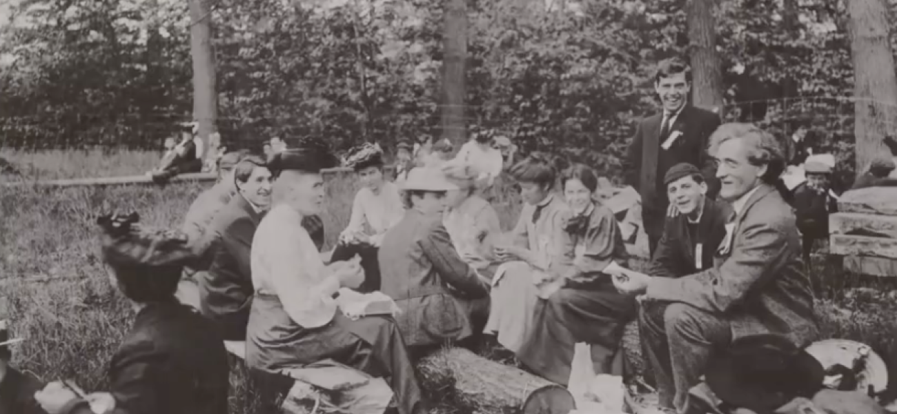 A historic photo showing people eating a picnic