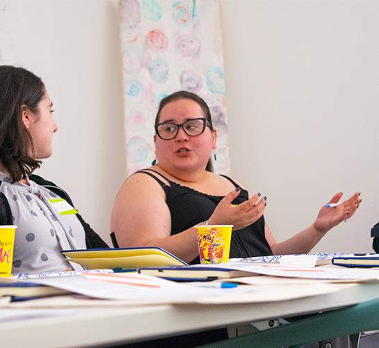 group of four people sit at a table talking