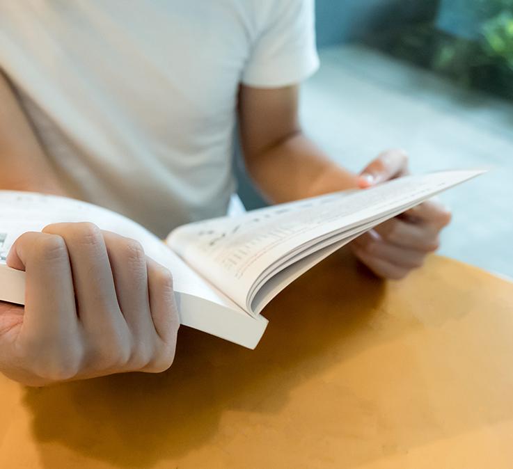 kids hands holding open a book while sitting at a school desk