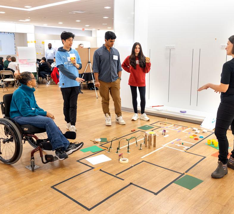 group of people in an open room looking at some plans on the ground