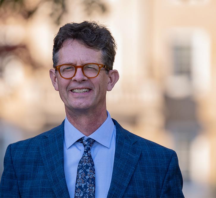 man with glasses and a blue suit standing outside