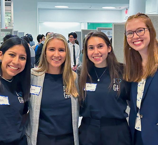 four undergraduate students pose and smile at a poster event