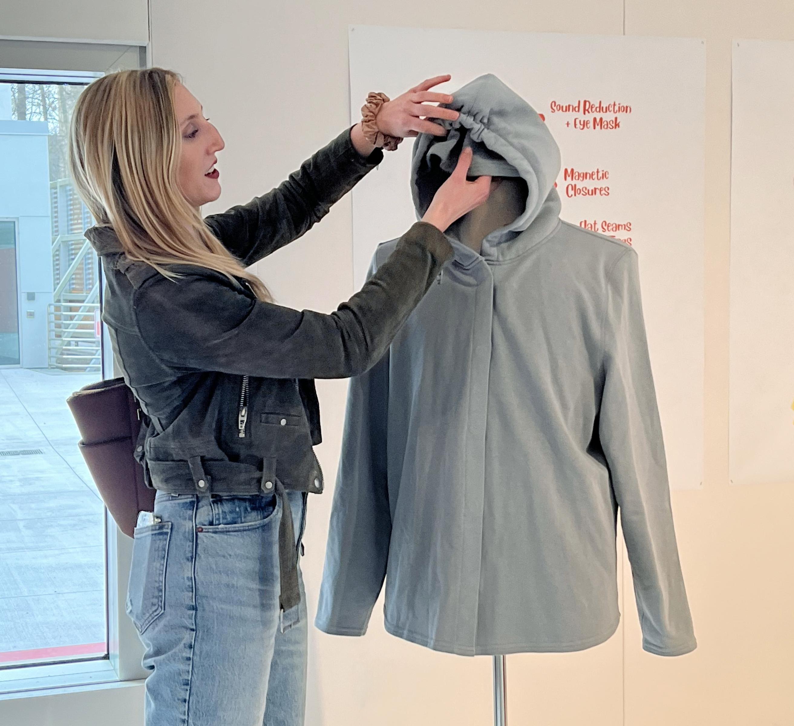 Julia DeNey ’20 demonstrates the hidden functions of a sweatshirt in the exhibit.