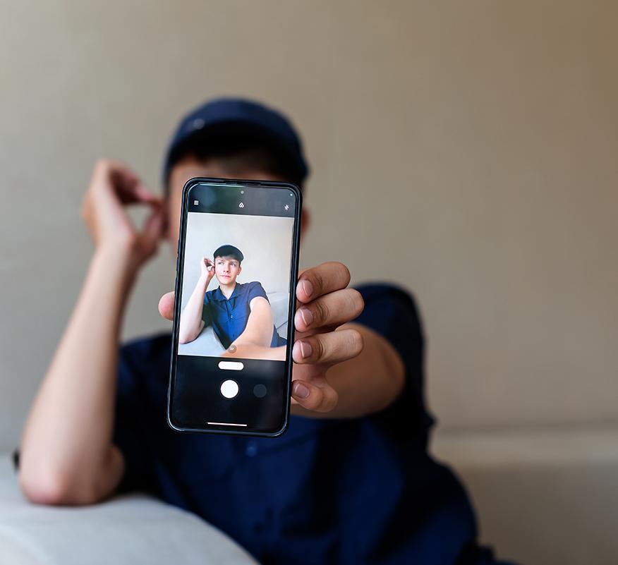 person holding a phone in front of their face with the screen turned towards the camera a photo of themselves on the screen