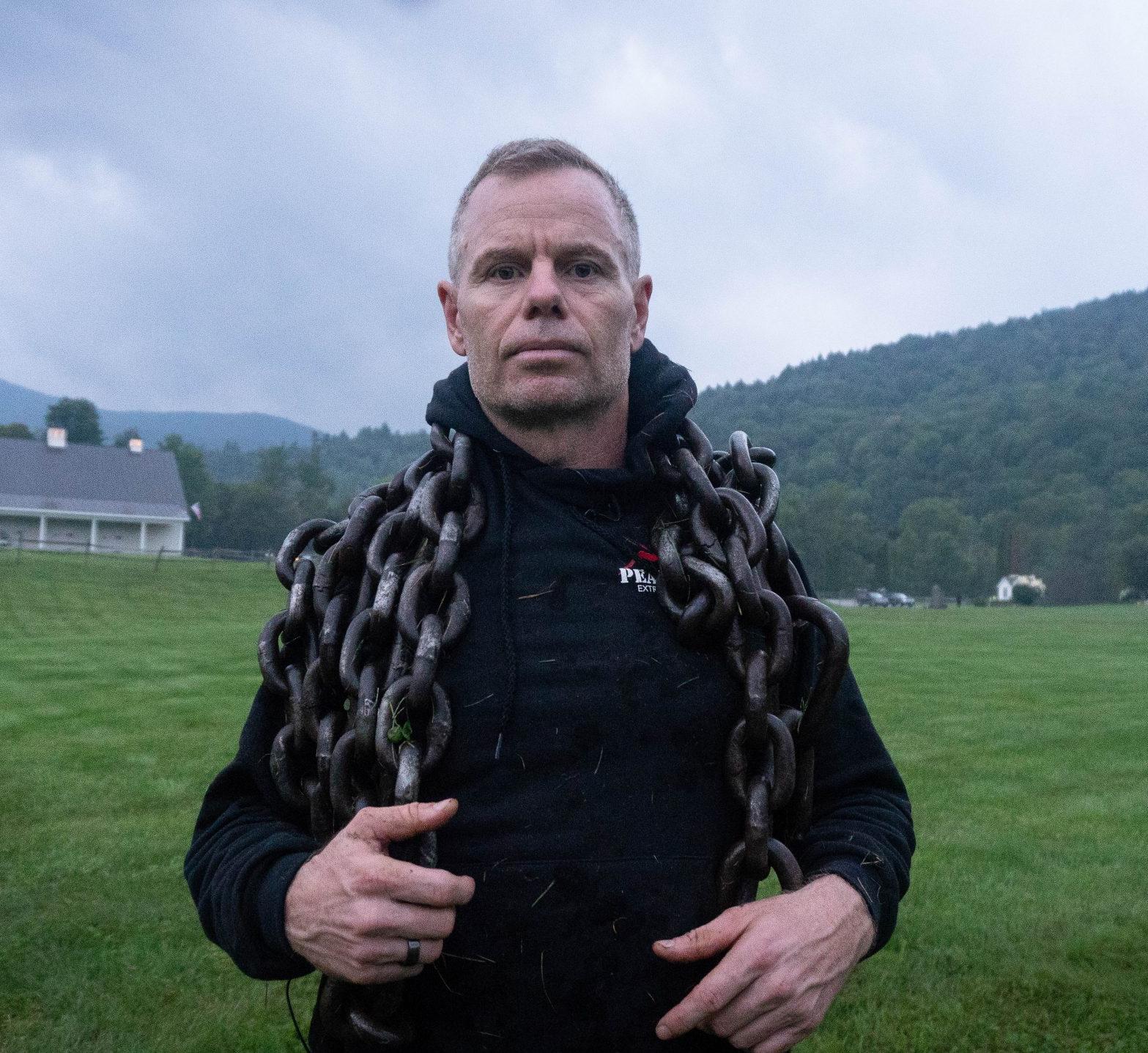 man on a hillside with a large chain draped over his shoulders