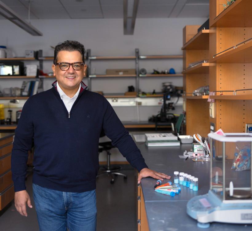 man standing in a laboratory with his hand leaning on a counter