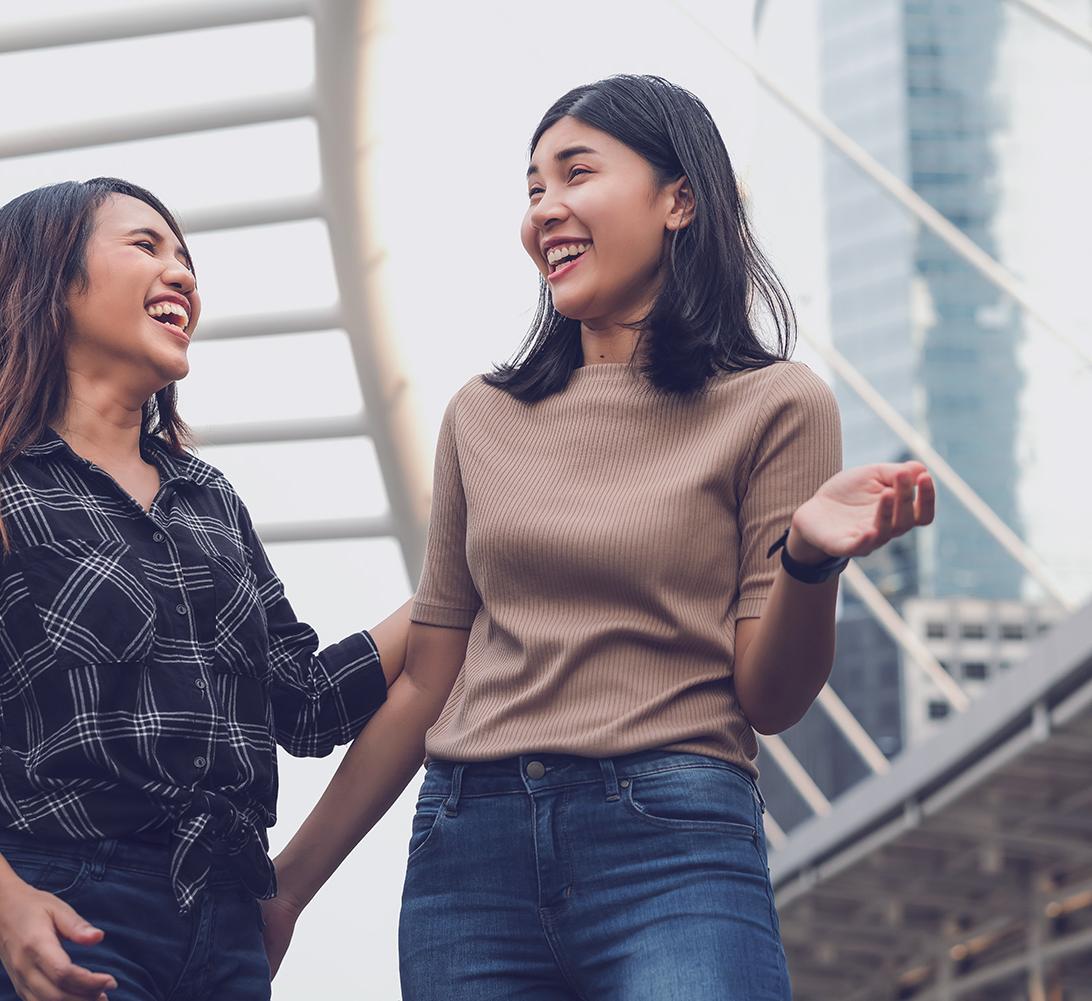 two women laughing outdoors in an urban setting