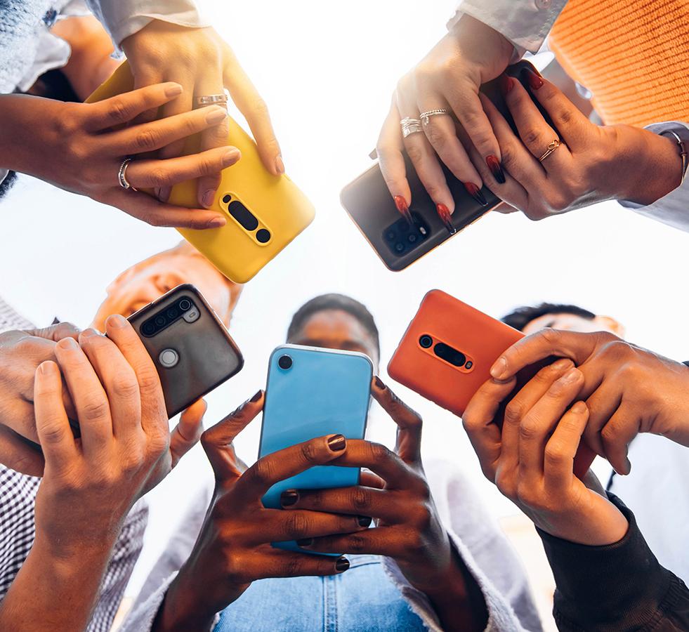a circle of young people's hands holding phones, viewed from below