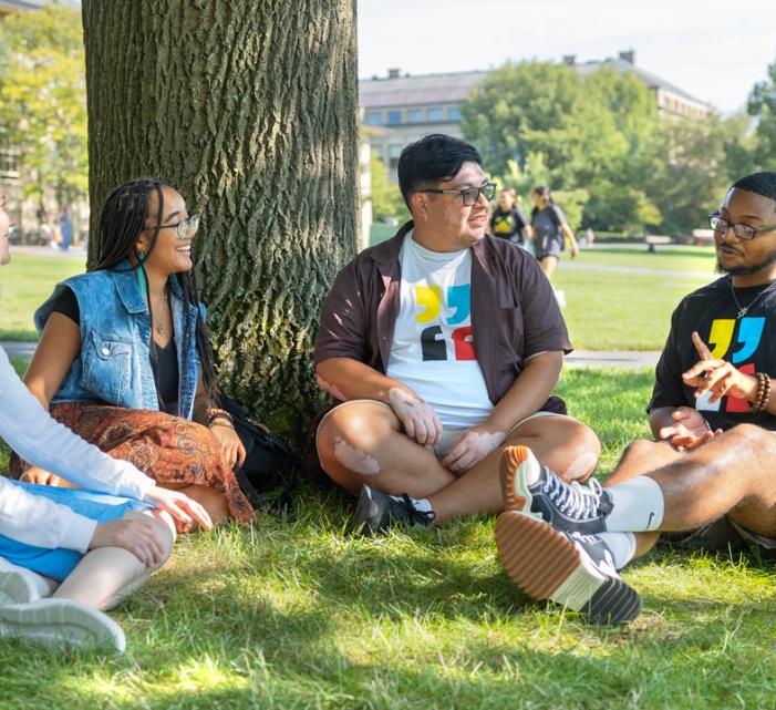 Two students sit and talk in the arts quad with freed of expression theme year tshirts on