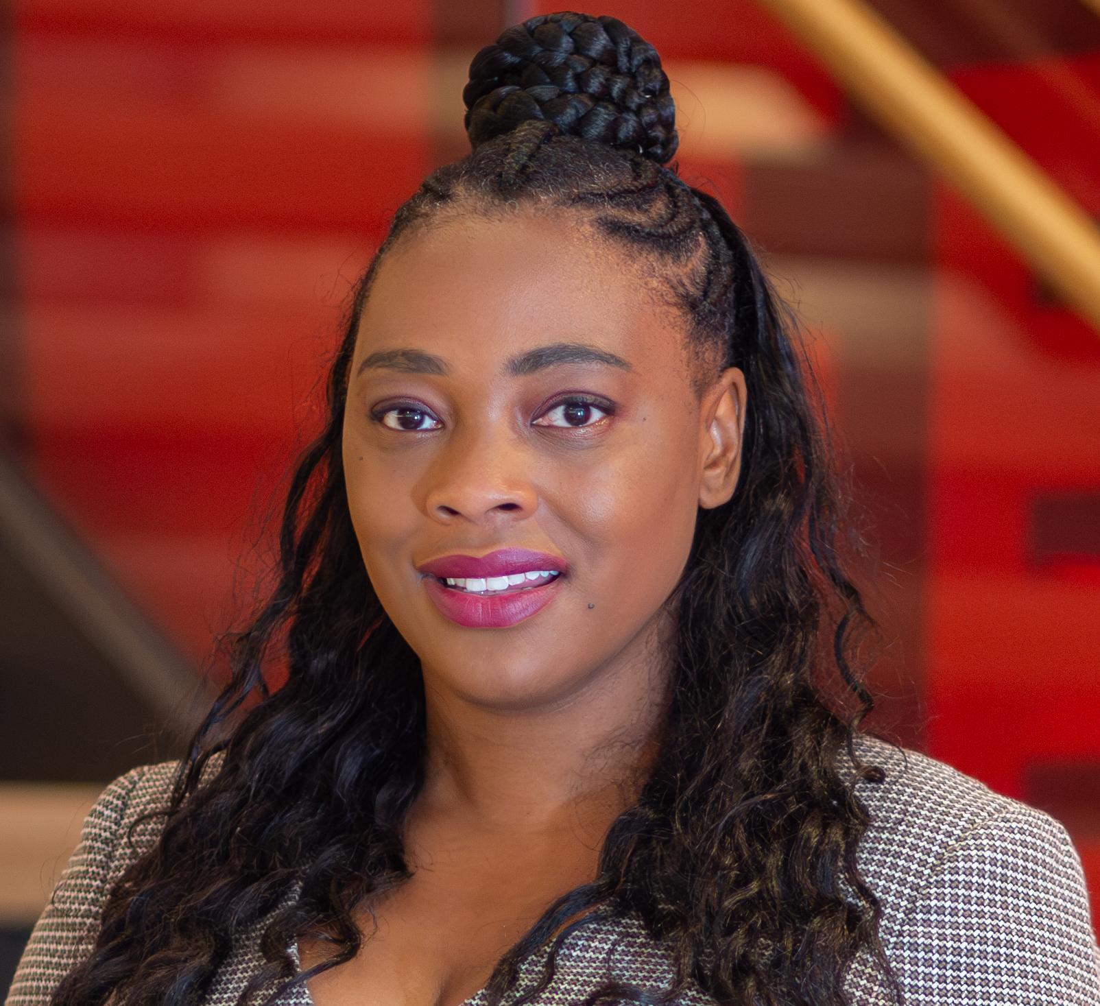 woman in a grey top in front of a red wall