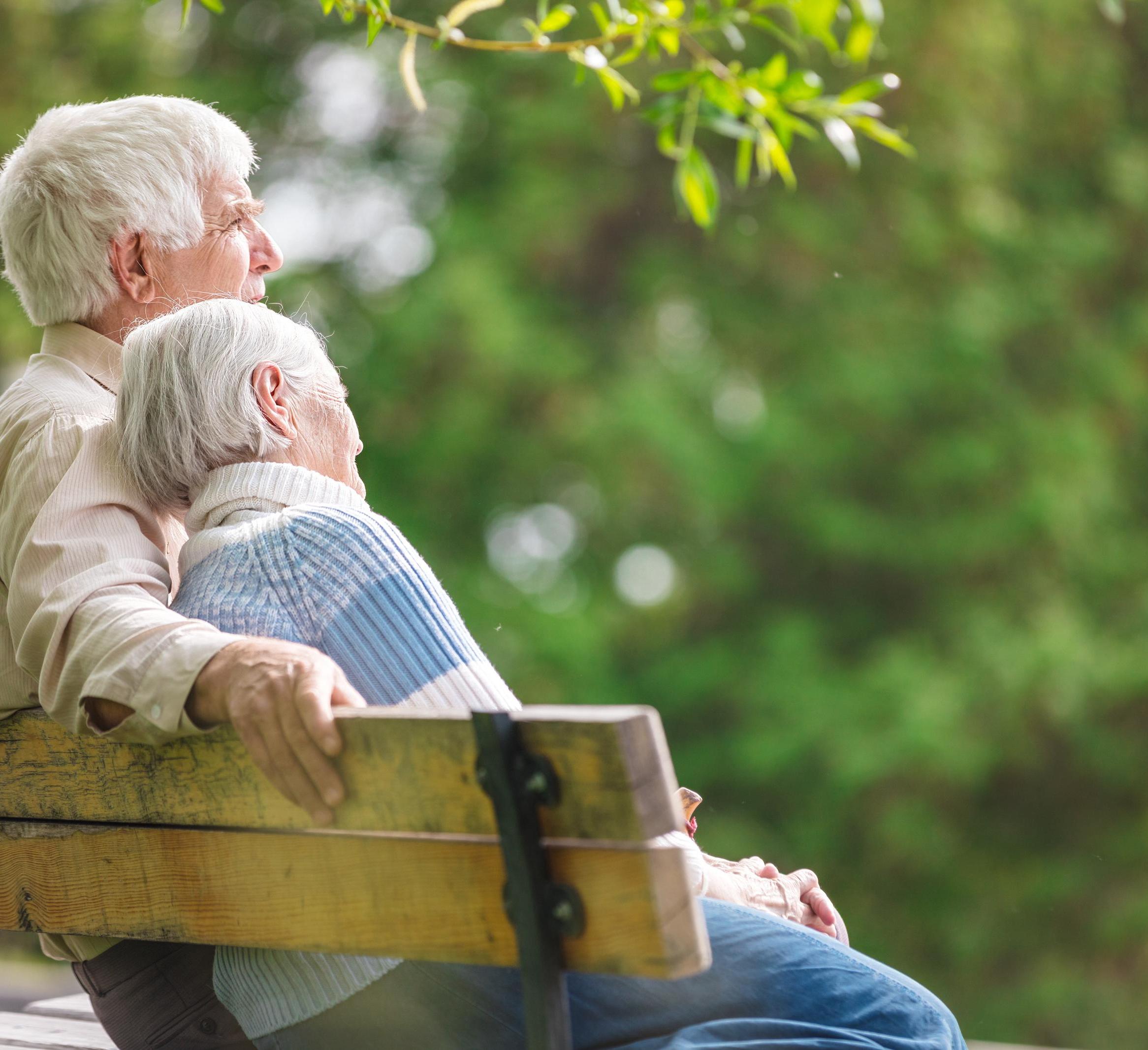 An older couple sits on a bench 