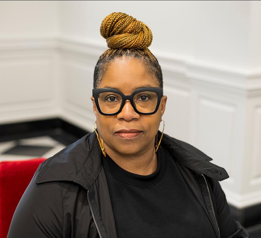 portrait of a woman in black framed glasses looking at the camera