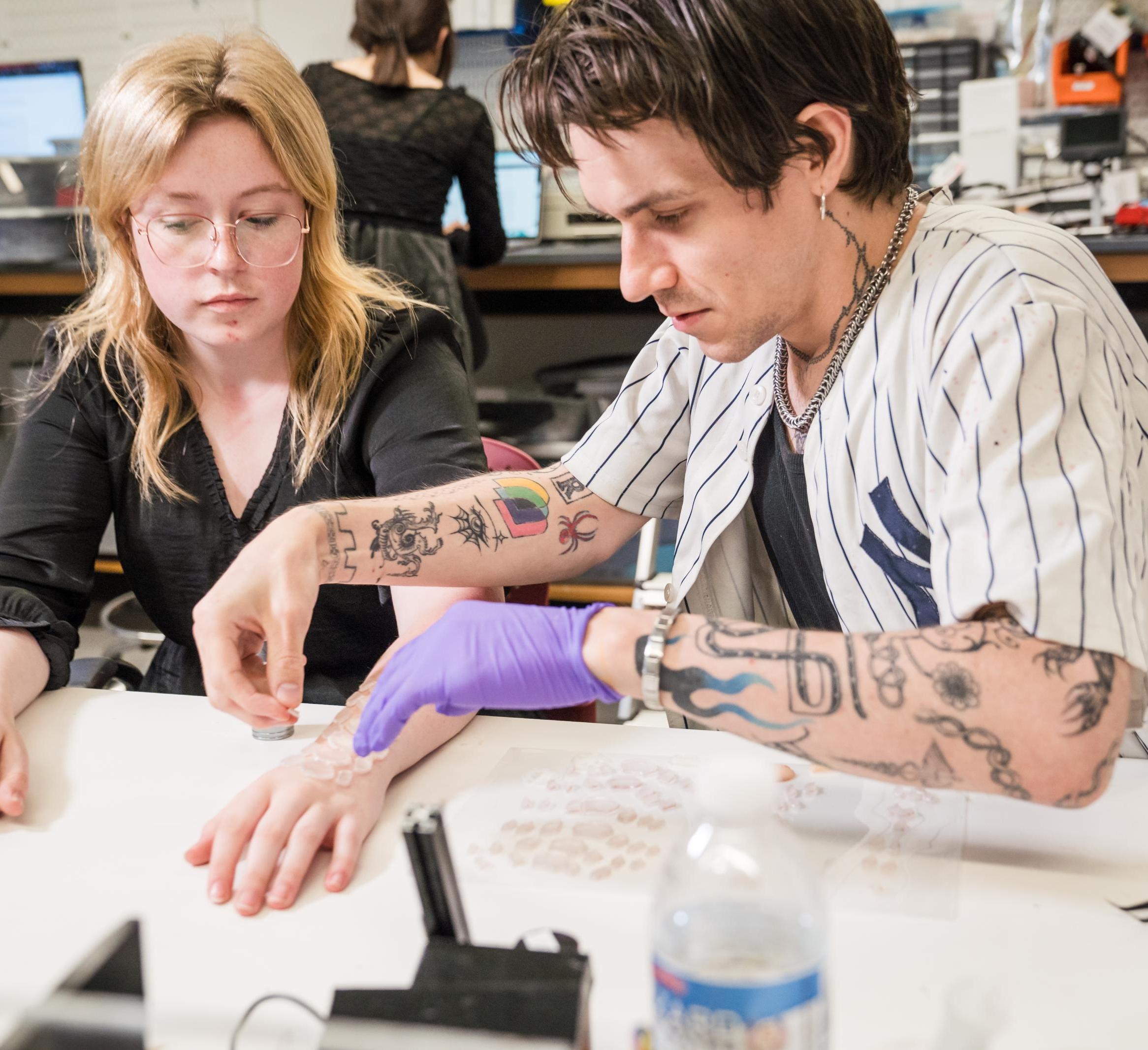 Joe George applies a smart temporary-tattoo to a model