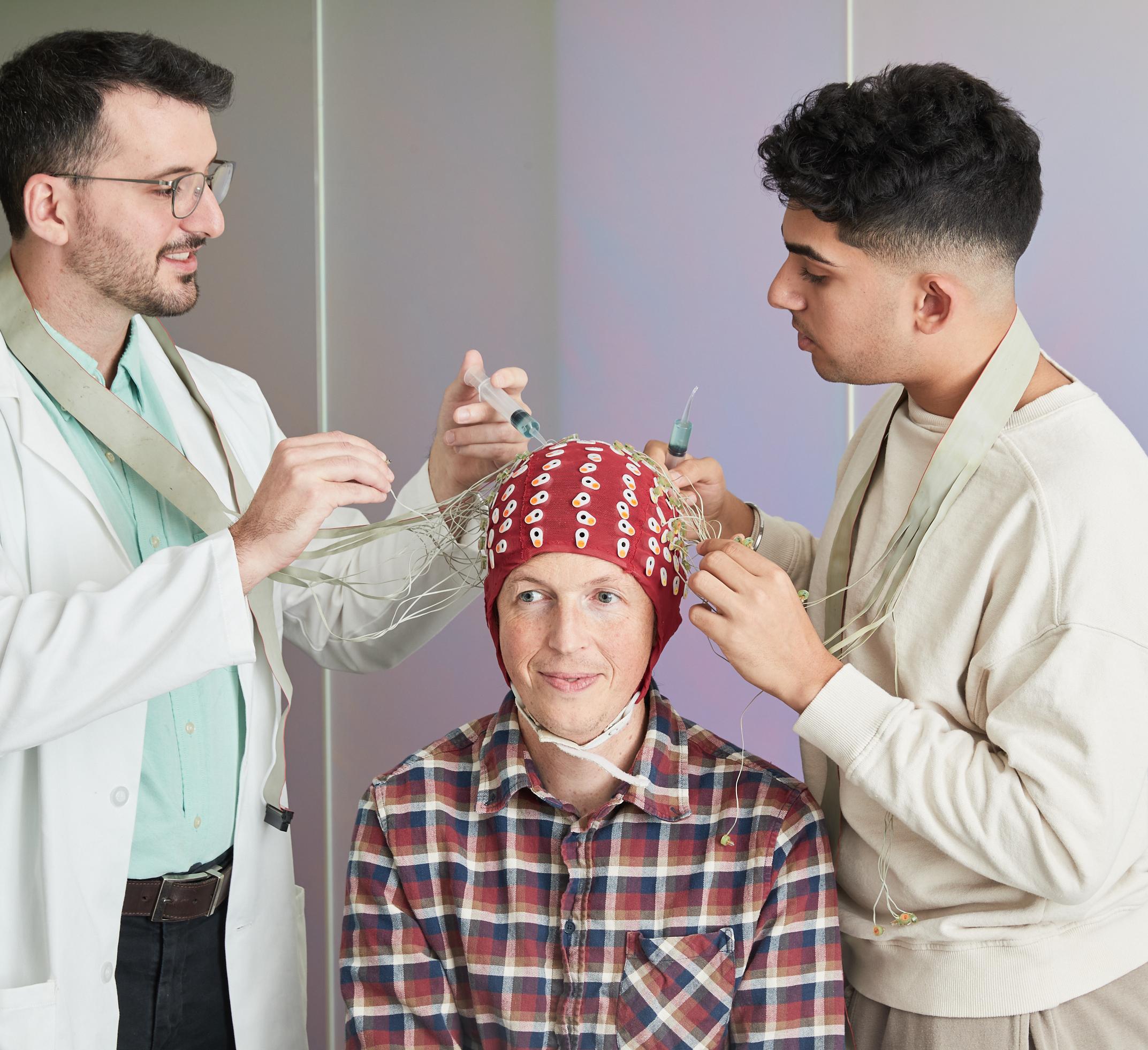 Two lab techs put an EEG cap on a patient